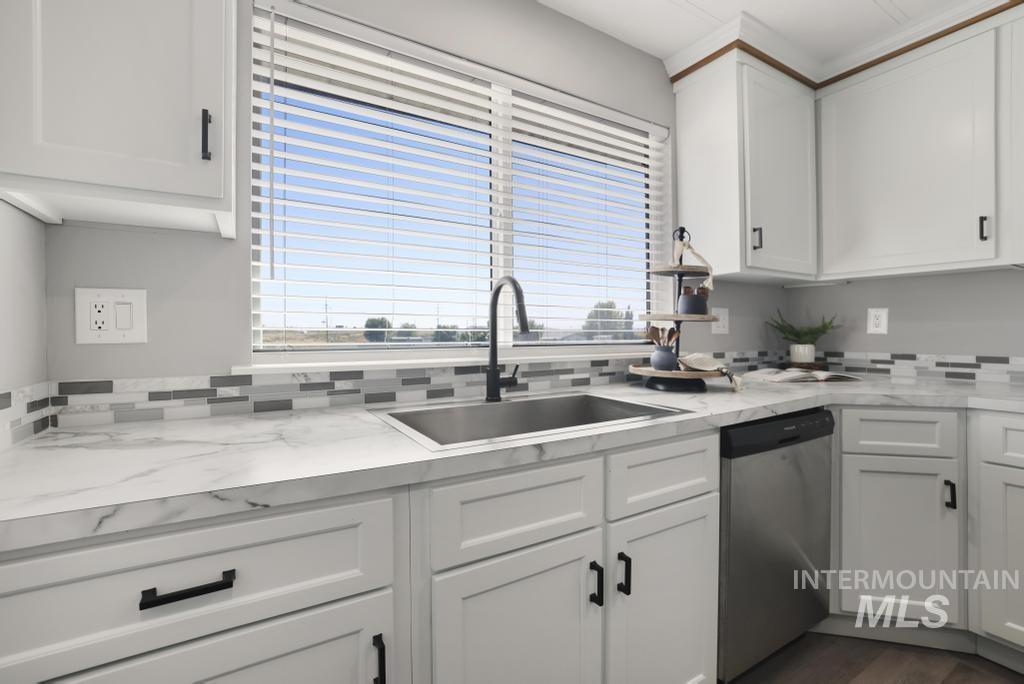 Kitchen with white cabinets, stainless steel dishwasher, dark wood finished floors, and decorative backsplash