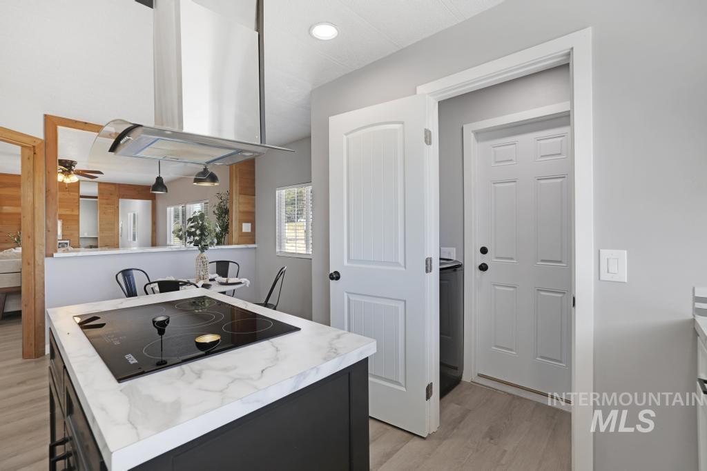 Kitchen with light countertops, light wood-style flooring, island exhaust hood, black electric stovetop, and recessed lighting