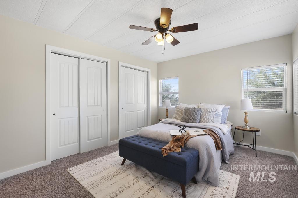 Bedroom with multiple closets, carpet, and a ceiling fan