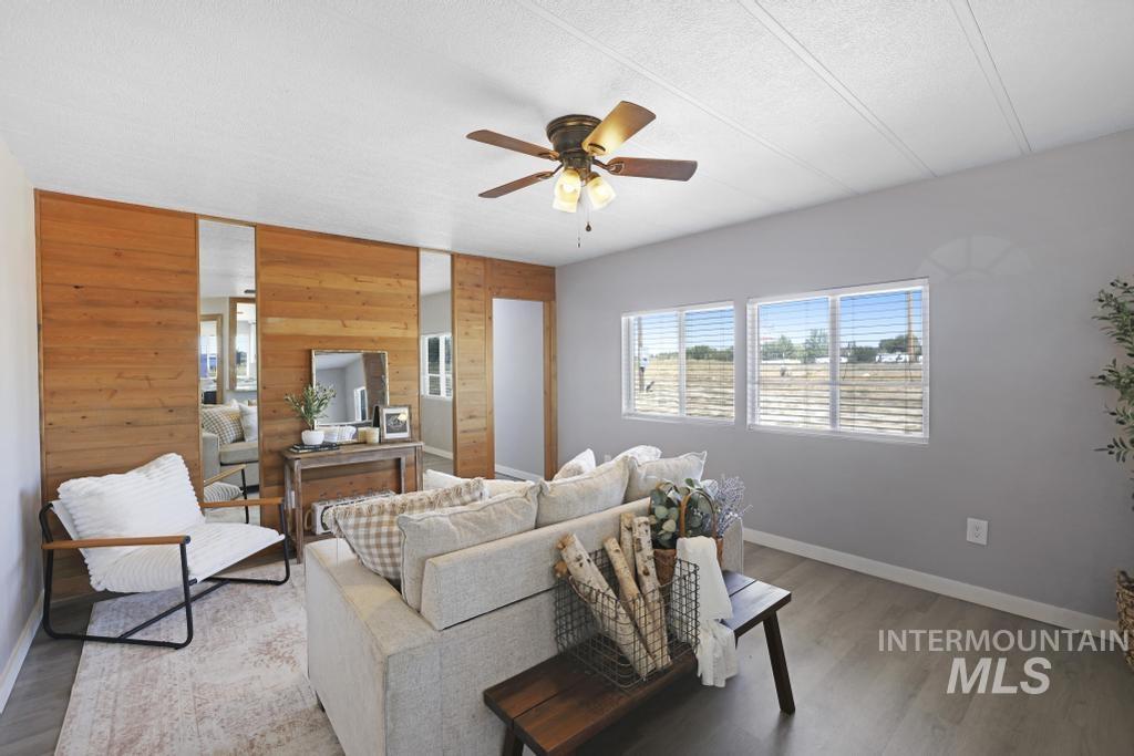 Living room with wood walls, wood finished floors, a ceiling fan, and a textured ceiling