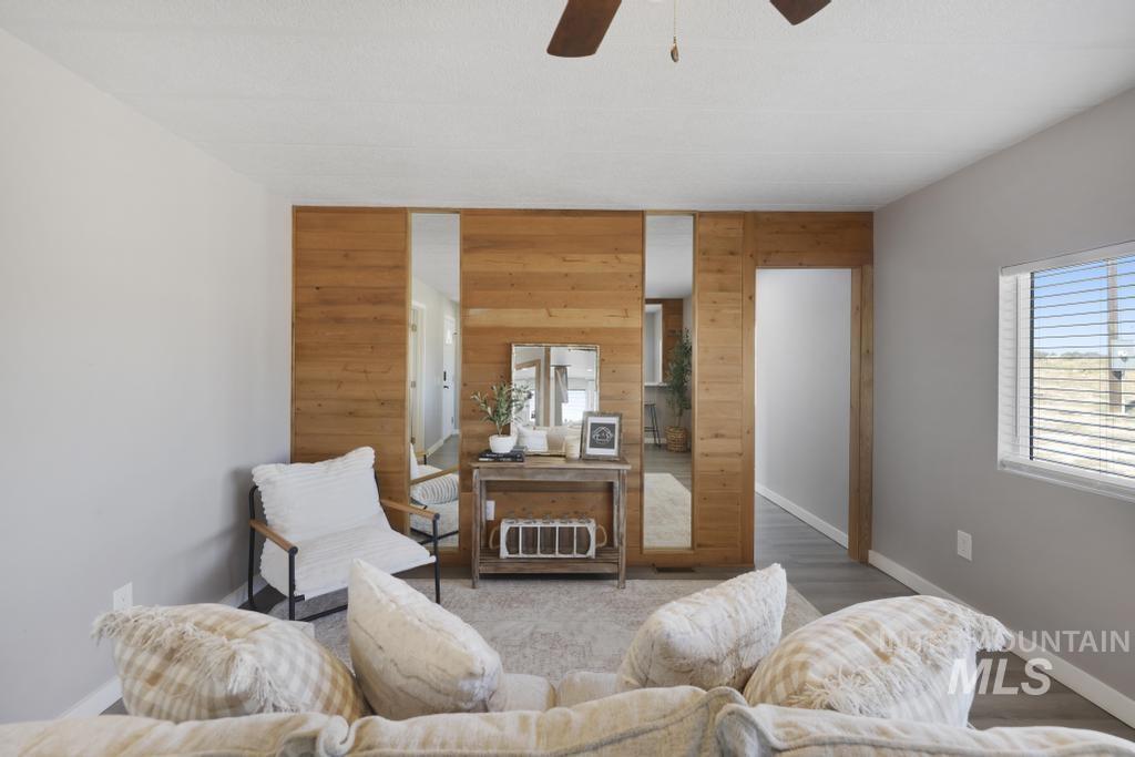 Living area with wooden walls, wood finished floors, and ceiling fan