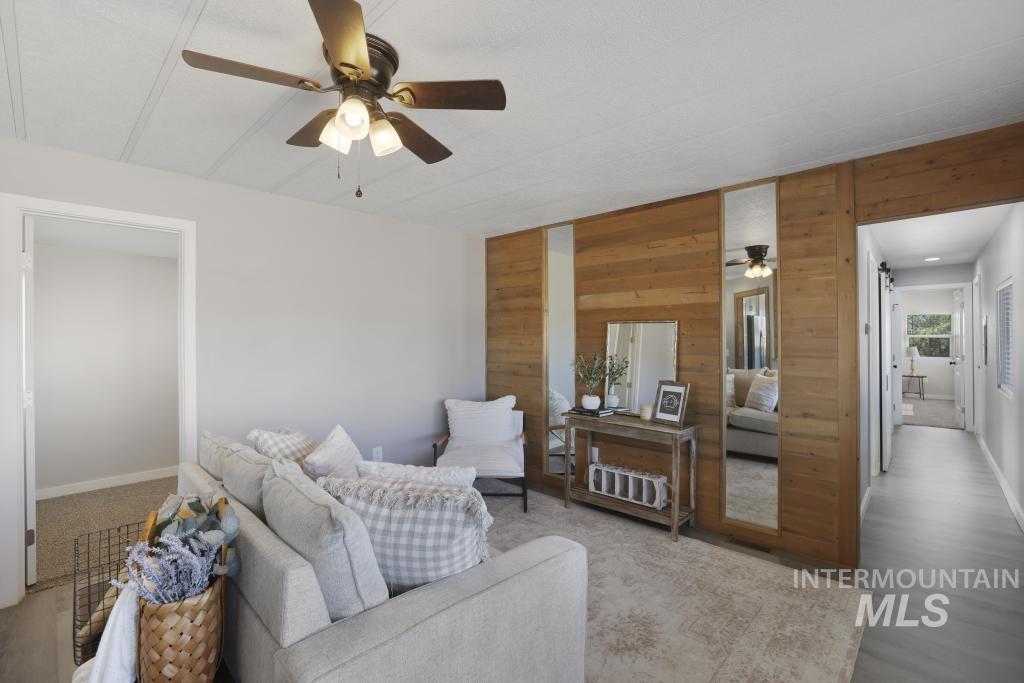 Living room featuring wood walls, ceiling fan, and wood finished floors