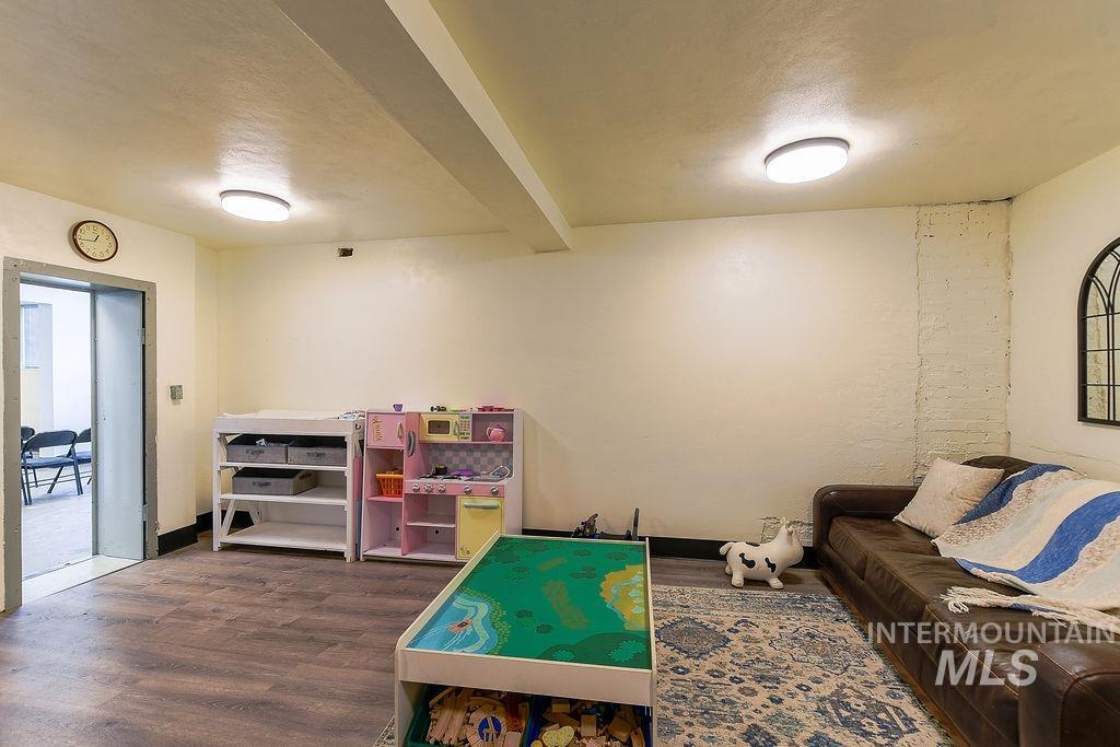 Rec room featuring a textured ceiling, dark wood finished floors, and beam ceiling