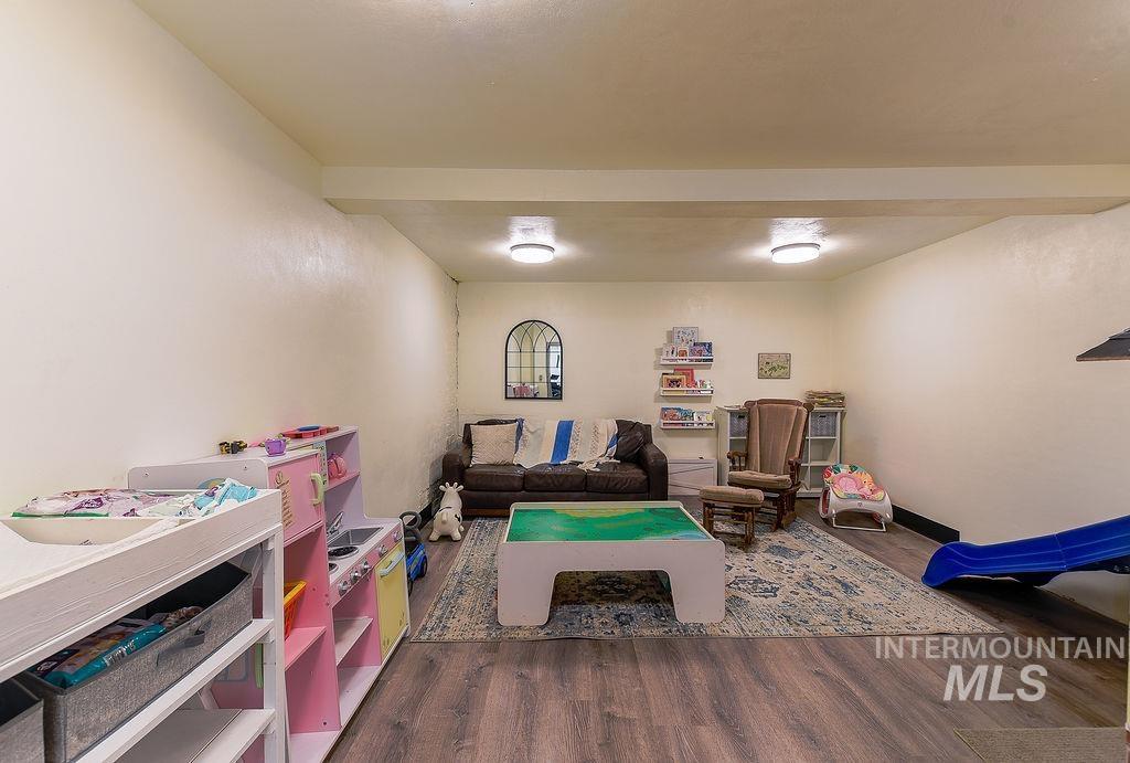 Rec room with dark wood-style flooring and beam ceiling