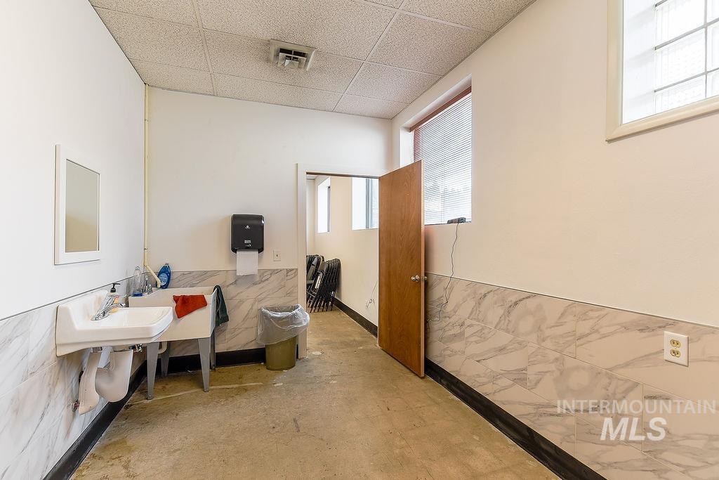 Bathroom featuring tile walls, a wainscoted wall, and a paneled ceiling