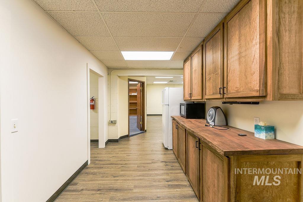 Kitchen with a drop ceiling, brown cabinetry, light wood-type flooring, butcher block countertops, and freestanding refrigerator