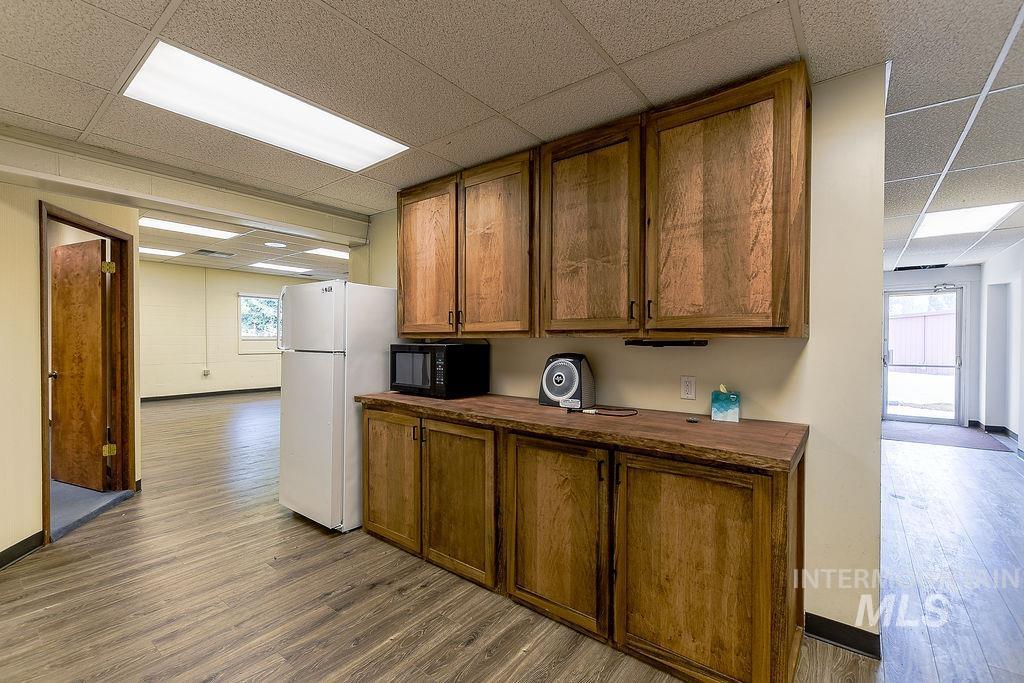 Kitchen with a paneled ceiling, brown cabinets, dark wood finished floors, wood counters, and black microwave