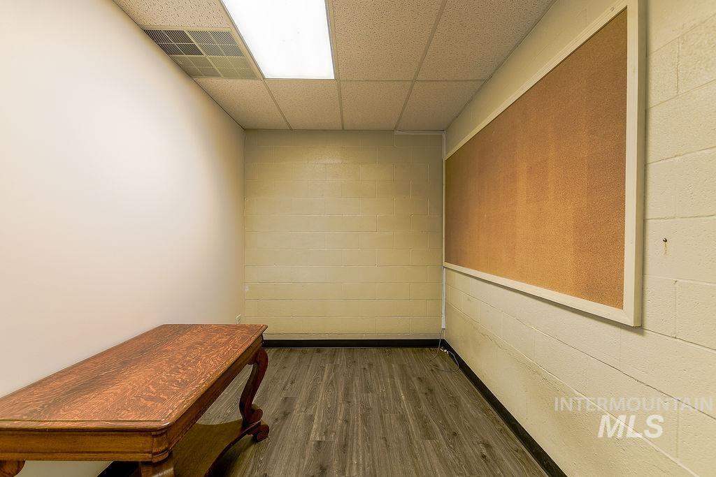 Hall with a paneled ceiling, dark wood-type flooring, and concrete block wall