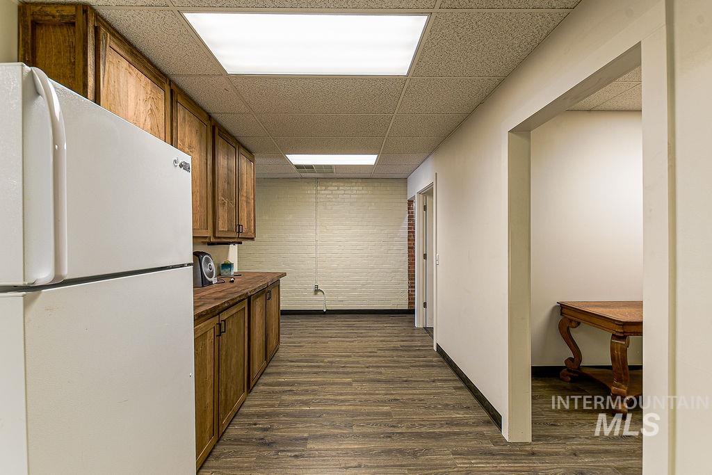 Kitchen with freestanding refrigerator, brown cabinetry, dark wood-style floors, wooden counters, and a paneled ceiling