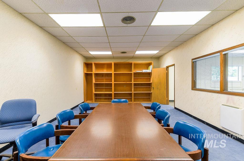 Carpeted office space featuring a textured wall, a drop ceiling, and built in shelves