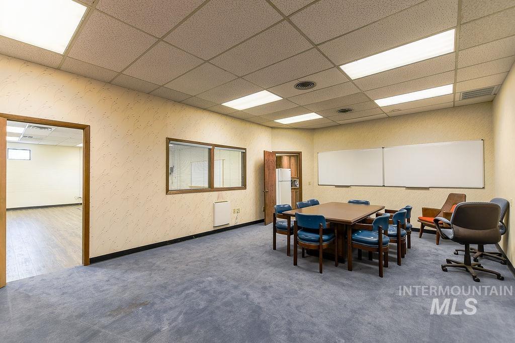 Carpeted dining area with a paneled ceiling and wallpapered walls
