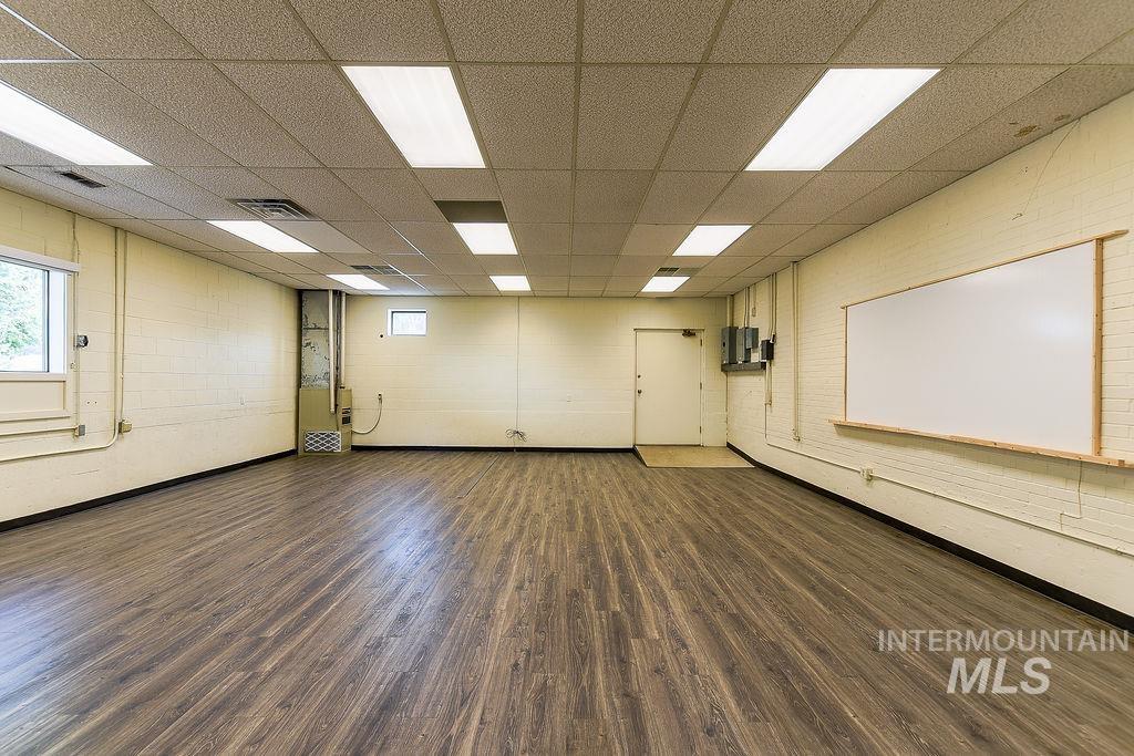 Empty room with dark wood finished floors and a drop ceiling
