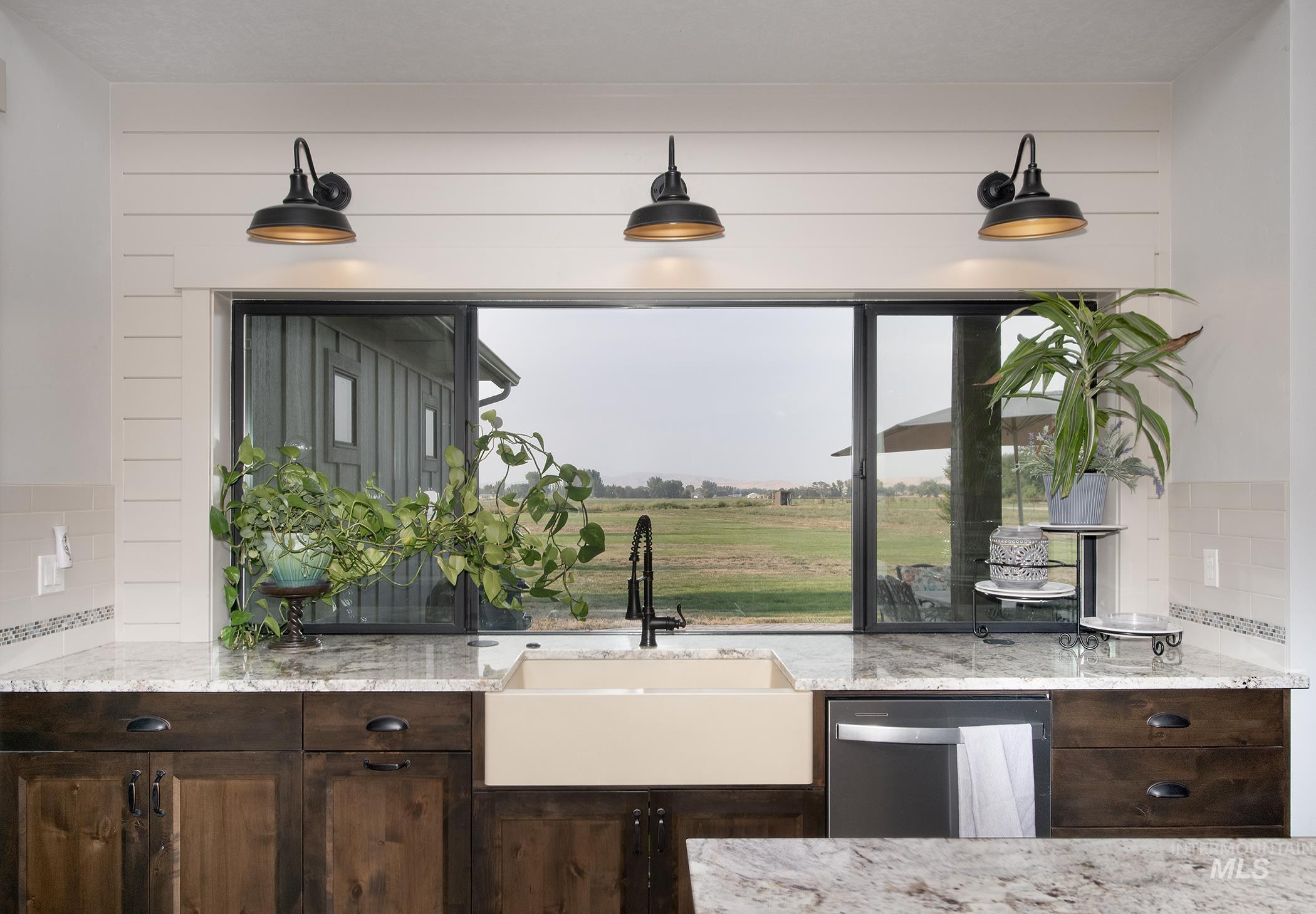 Kitchen featuring backsplash, dark brown cabinets, light stone countertops, and dishwasher