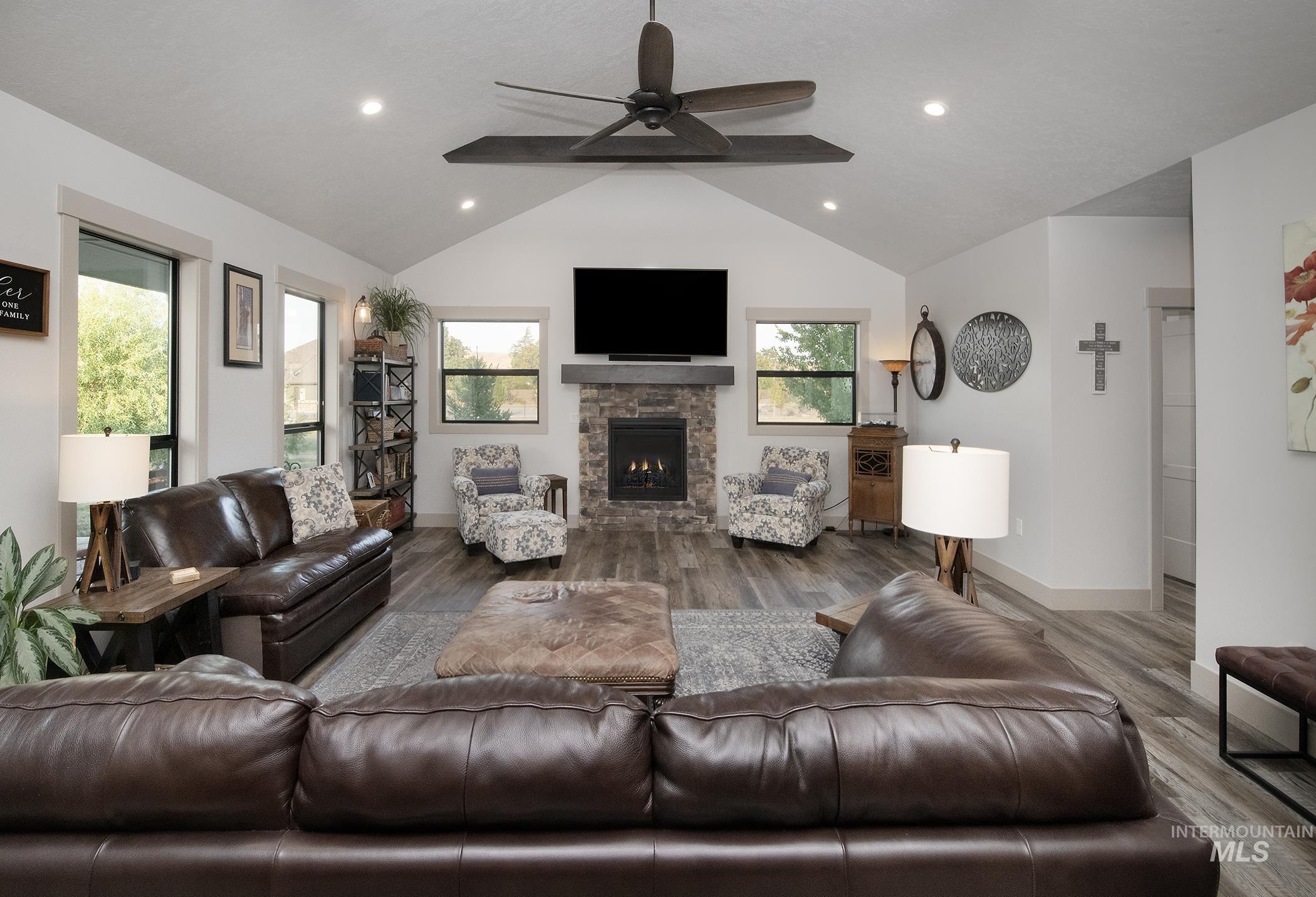 Living area with lofted ceiling, wood finished floors, a ceiling fan, a fireplace, and recessed lighting
