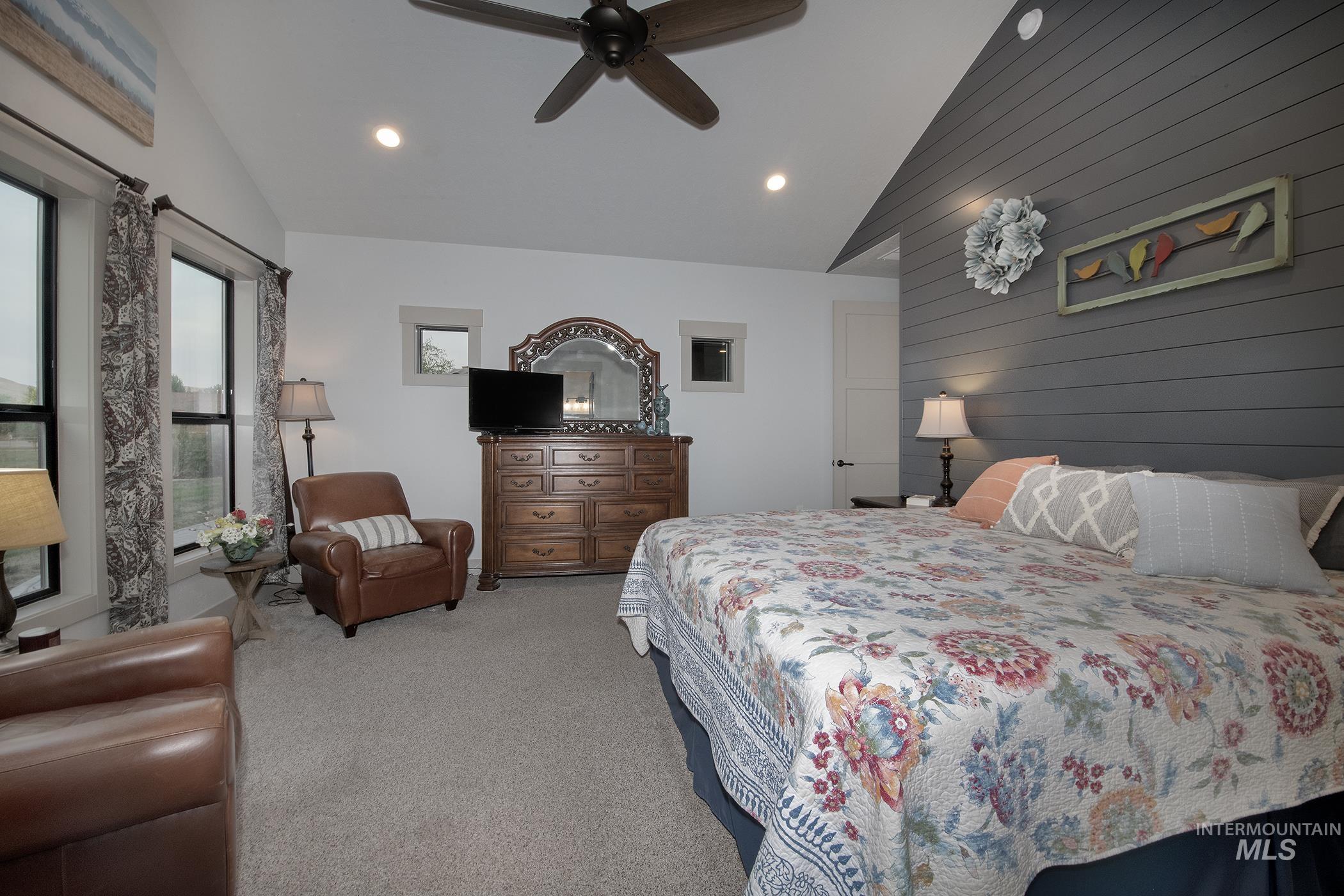Bedroom featuring vaulted ceiling, carpet, wood walls, recessed lighting, and ceiling fan