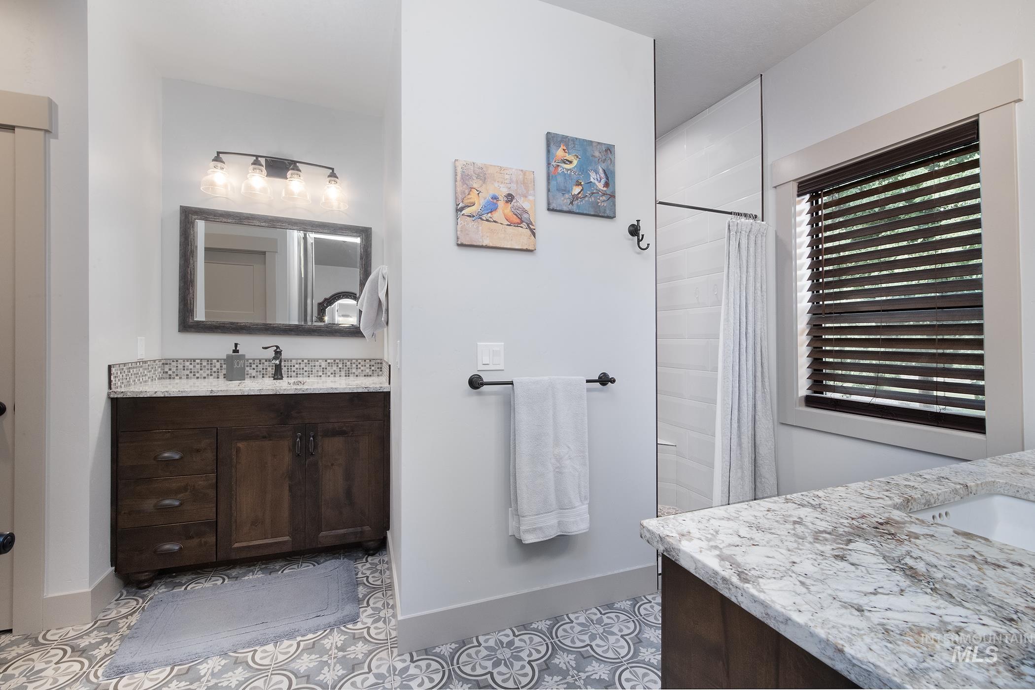 Bathroom featuring two vanities, a shower with curtain, and light tile patterned flooring