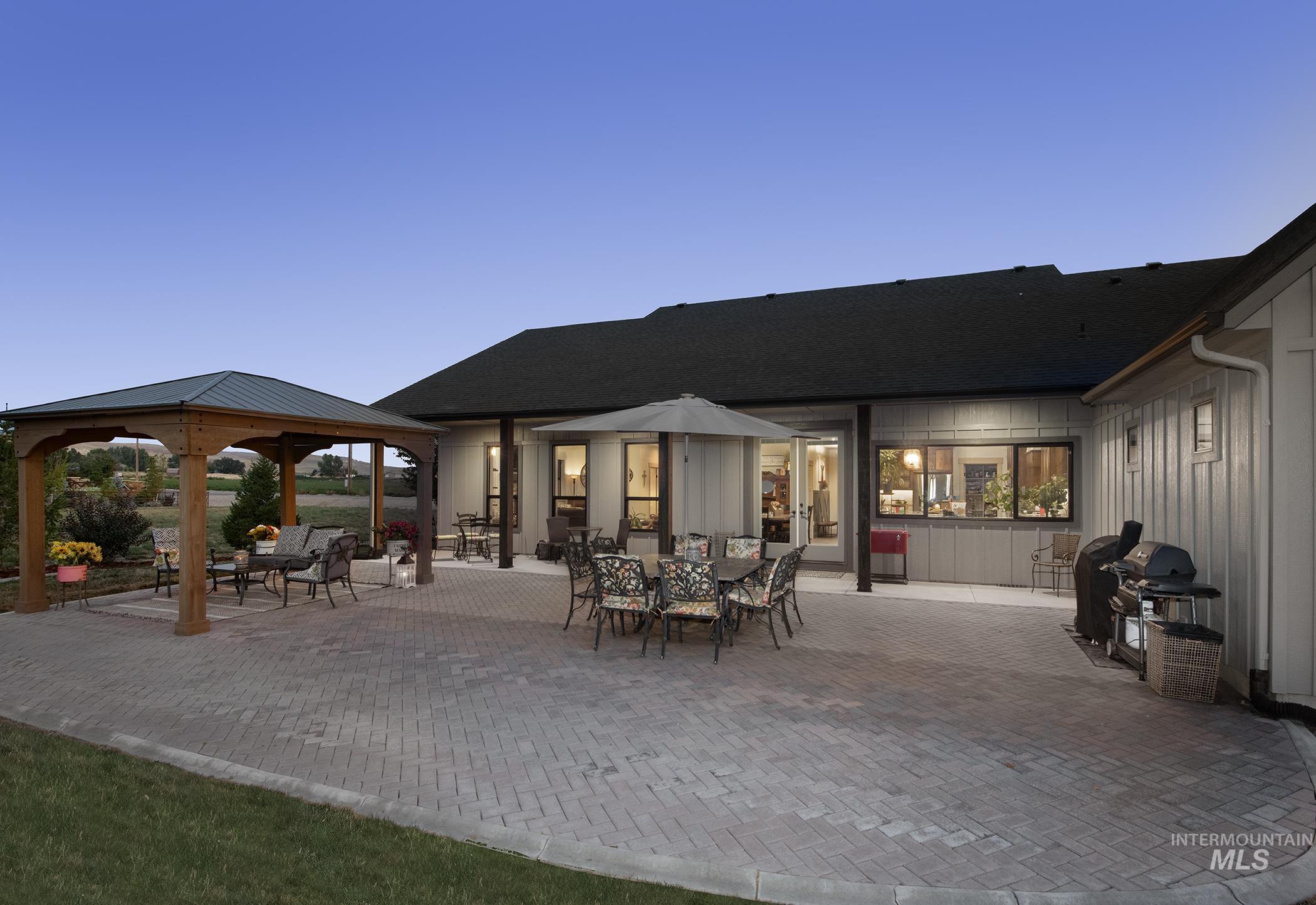 Rear view of property with a patio, a gazebo, a shingled roof, and board and batten siding