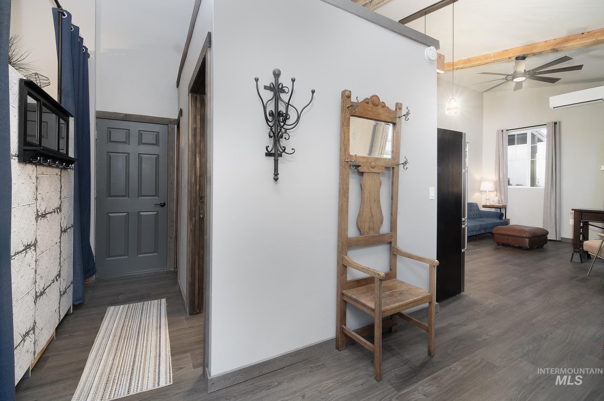 Hallway with dark wood finished floors, beam ceiling, and a wall unit AC
