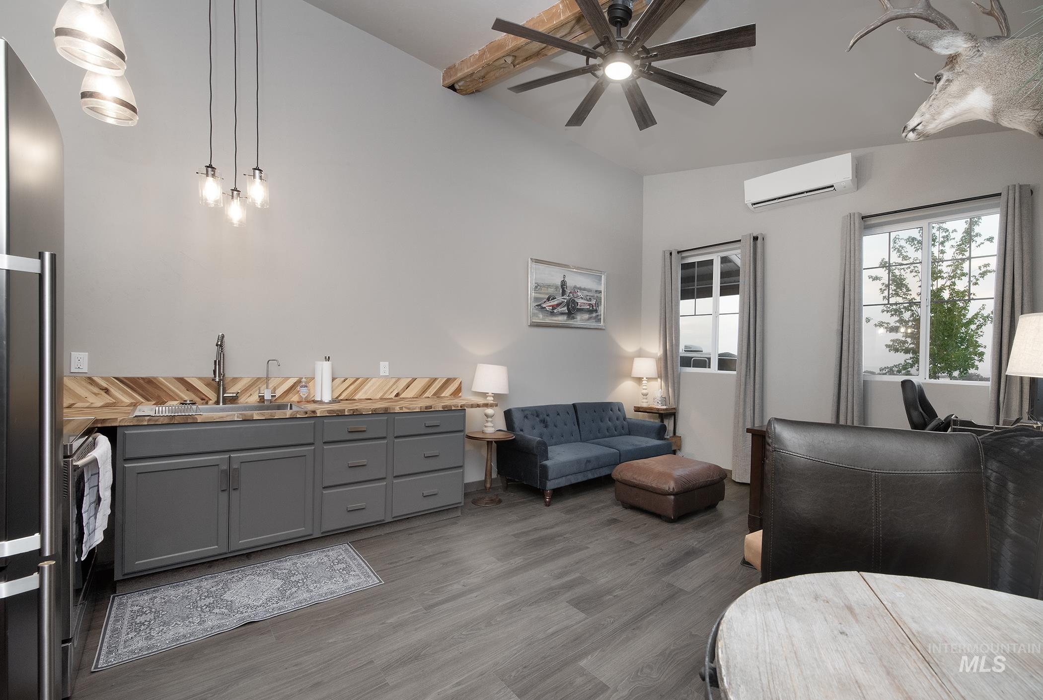 Living room with dark wood-type flooring, a wall mounted AC, ceiling fan, and lofted ceiling