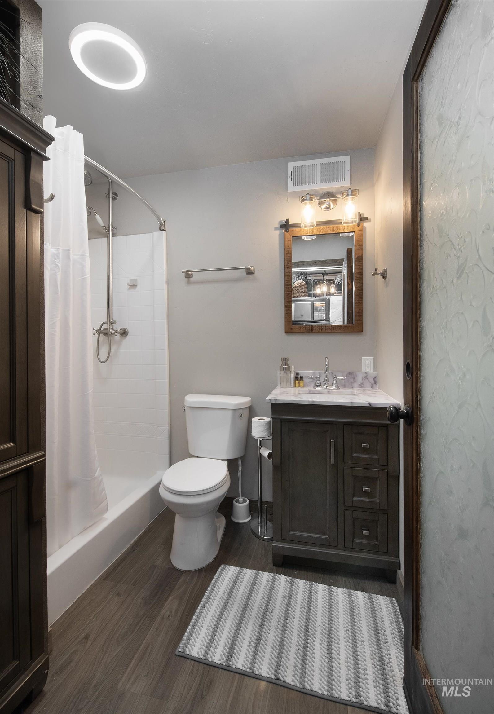 Bathroom with dark wood-style flooring, vanity, and a stall shower