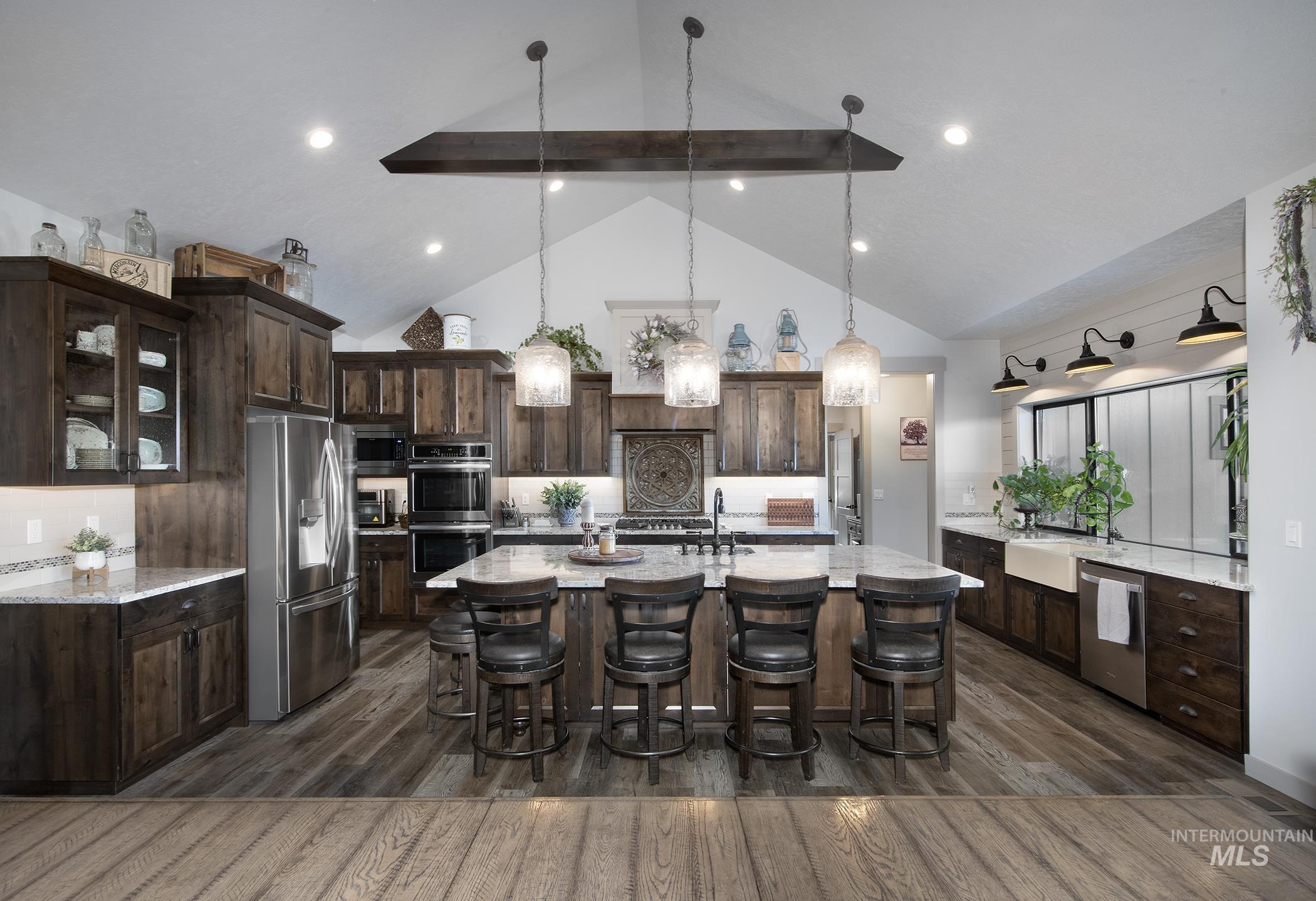 Kitchen featuring tasteful backsplash, dark brown cabinets, dark wood-style floors, a kitchen breakfast bar, and stainless steel appliances