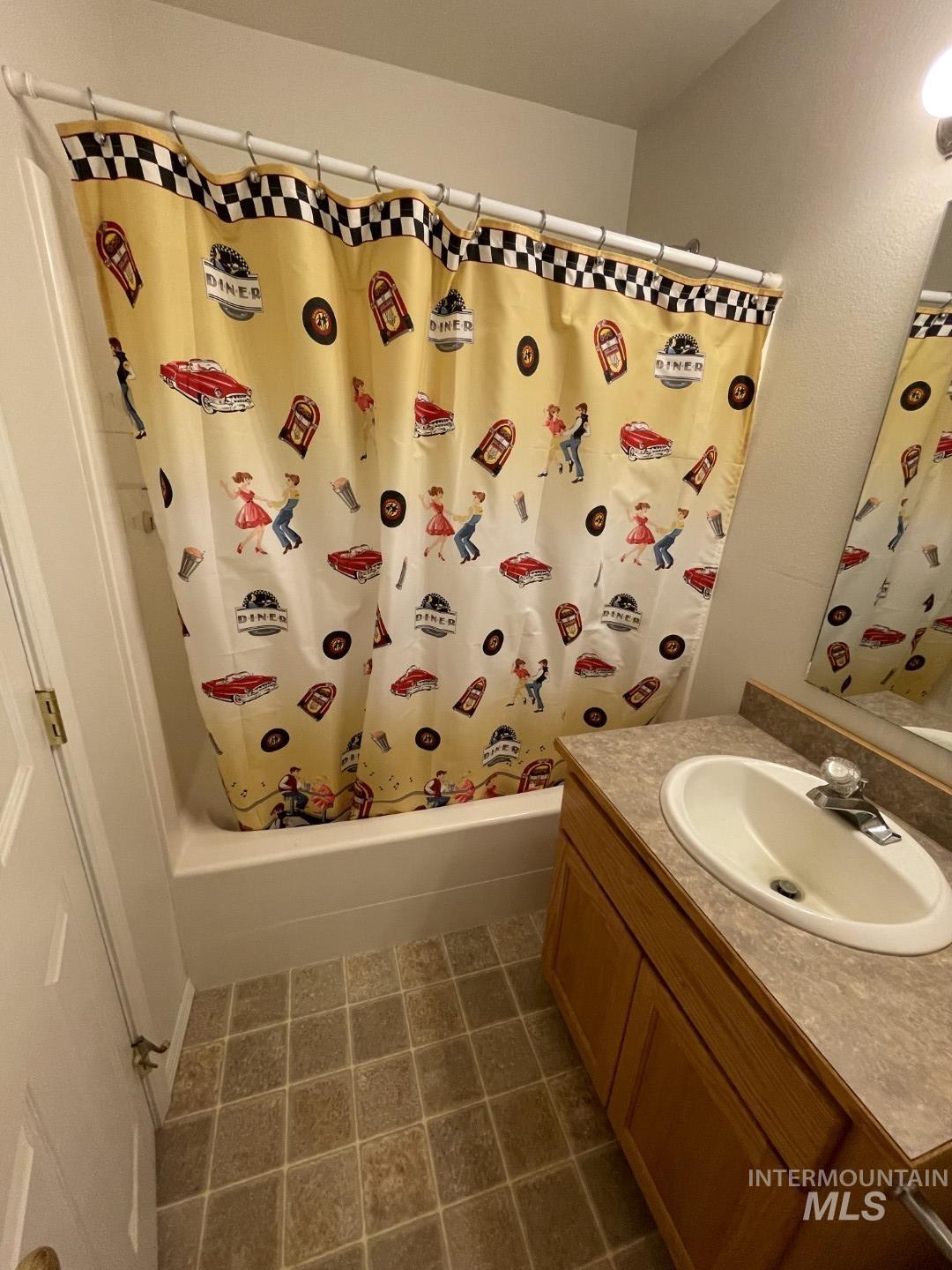 Full bath featuring shower / tub combo, vanity, and dark tile patterned floors