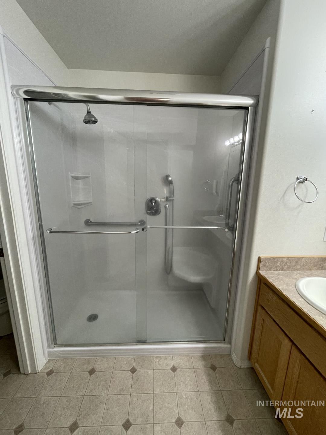 Full bathroom featuring vanity, a stall shower, and light tile patterned flooring