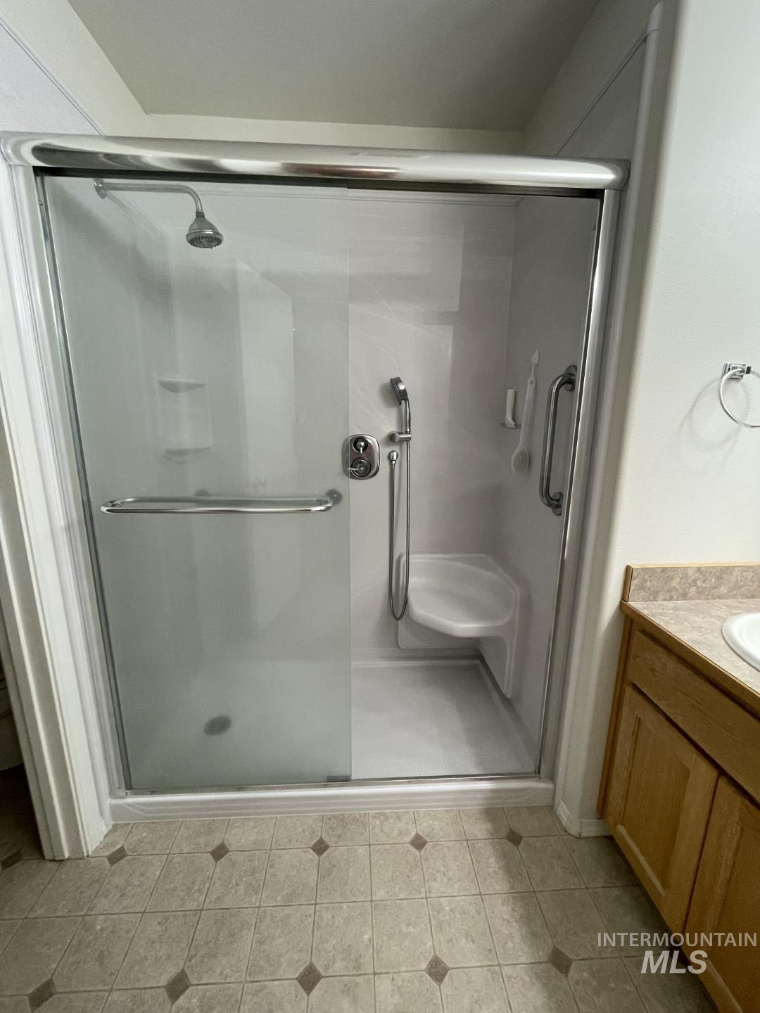 Full bathroom featuring vanity, a stall shower, and light tile patterned flooring