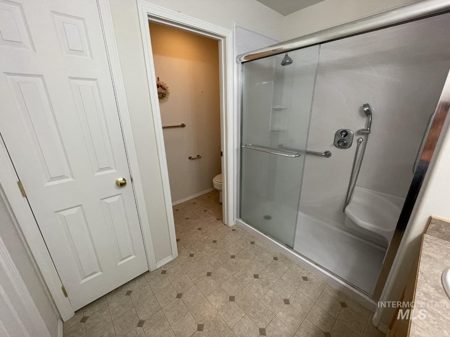 Full bath featuring a shower stall, vanity, and light floors