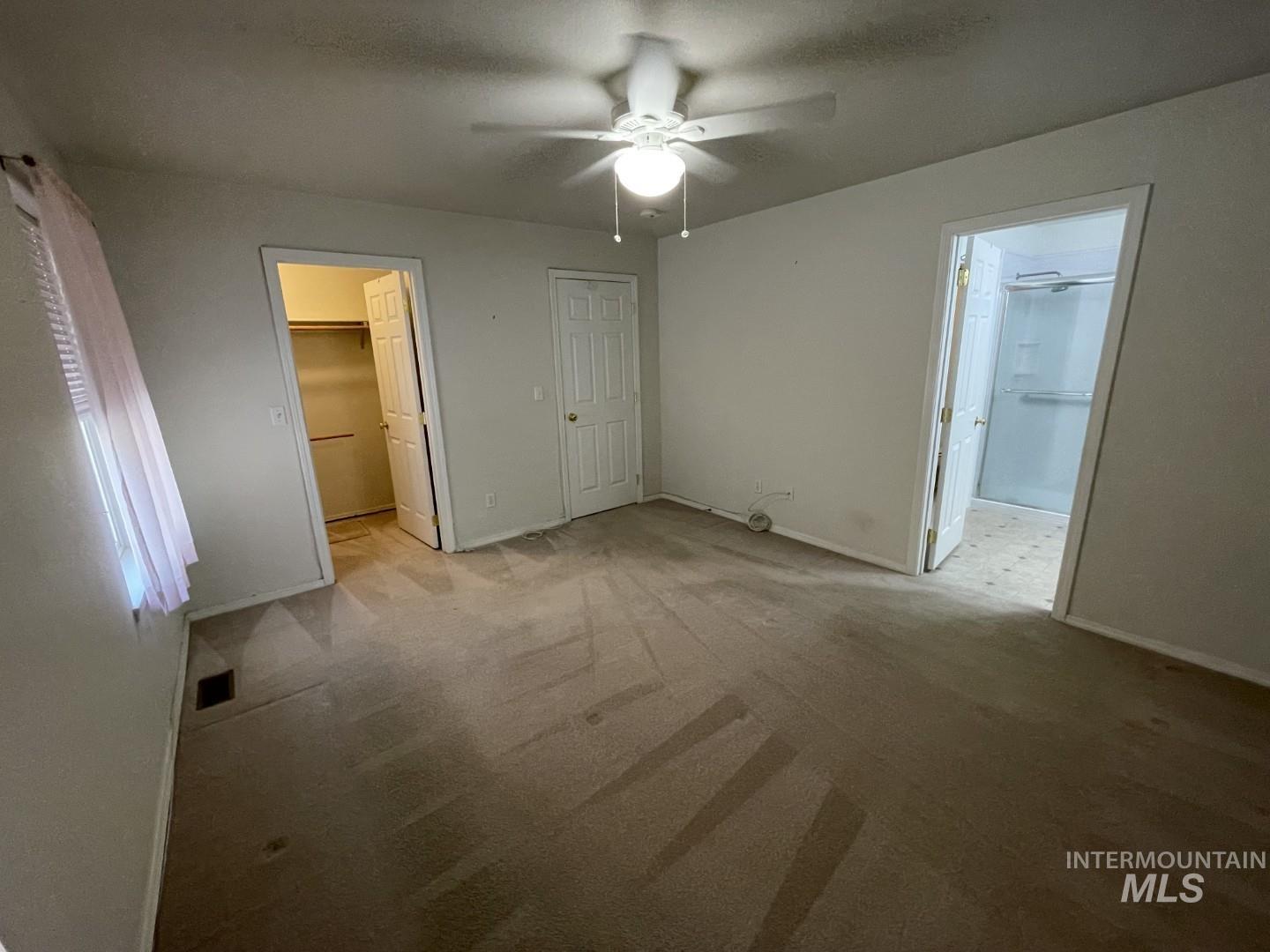 Unfurnished bedroom featuring a spacious closet, carpet, and ceiling fan