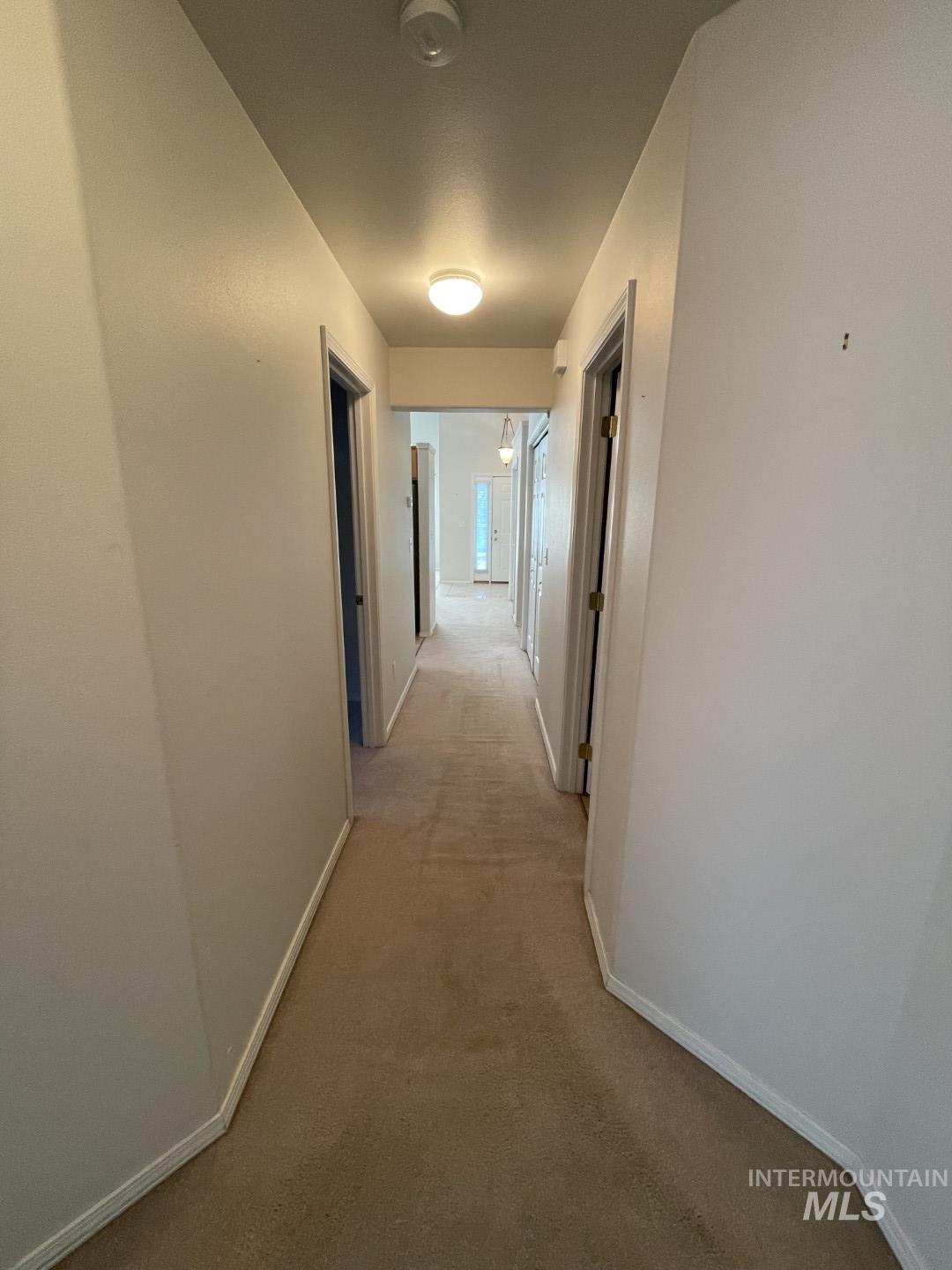 Hallway with light carpet and baseboards
