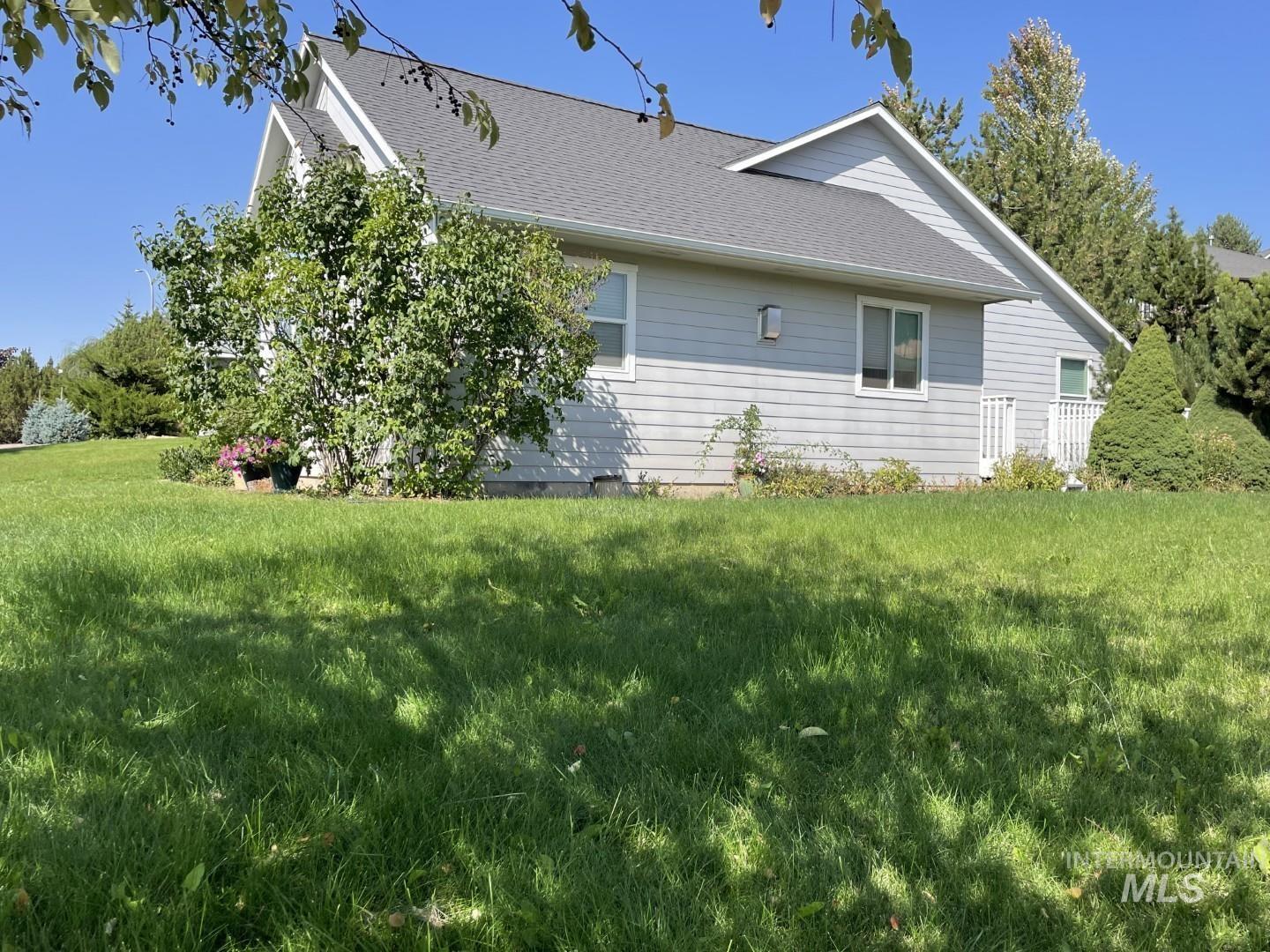 View of side of home featuring a shingled roof and a lawn