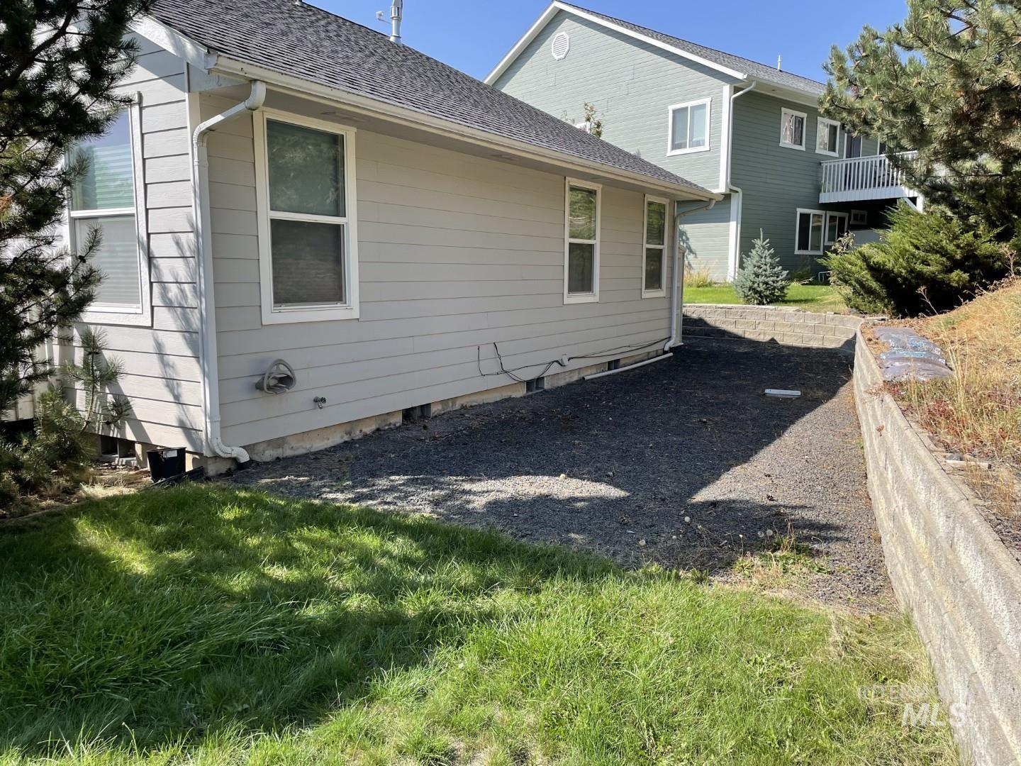 Rear view of property with a shingled roof, crawl space, and a lawn