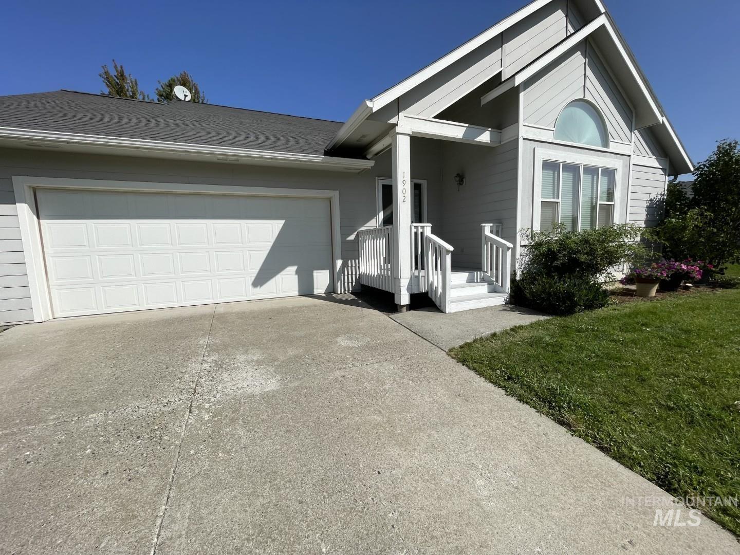 View of front of home featuring concrete driveway, a front yard, roof with shingles, and an attached garage