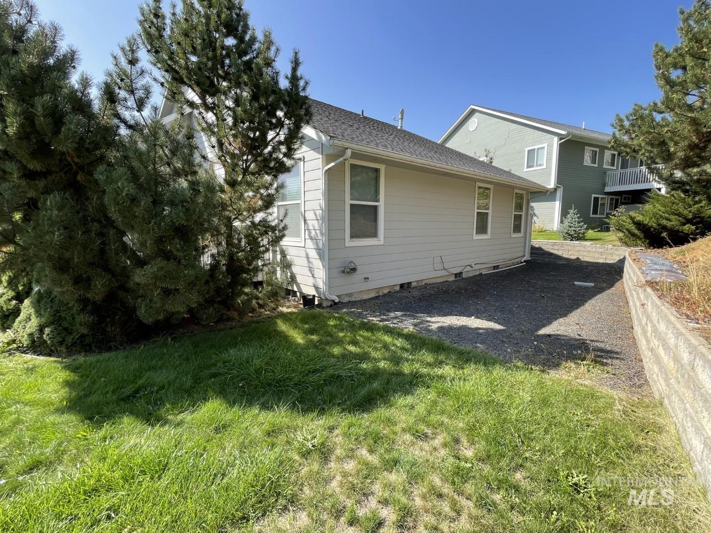 View of side of property featuring a lawn and a shingled roof