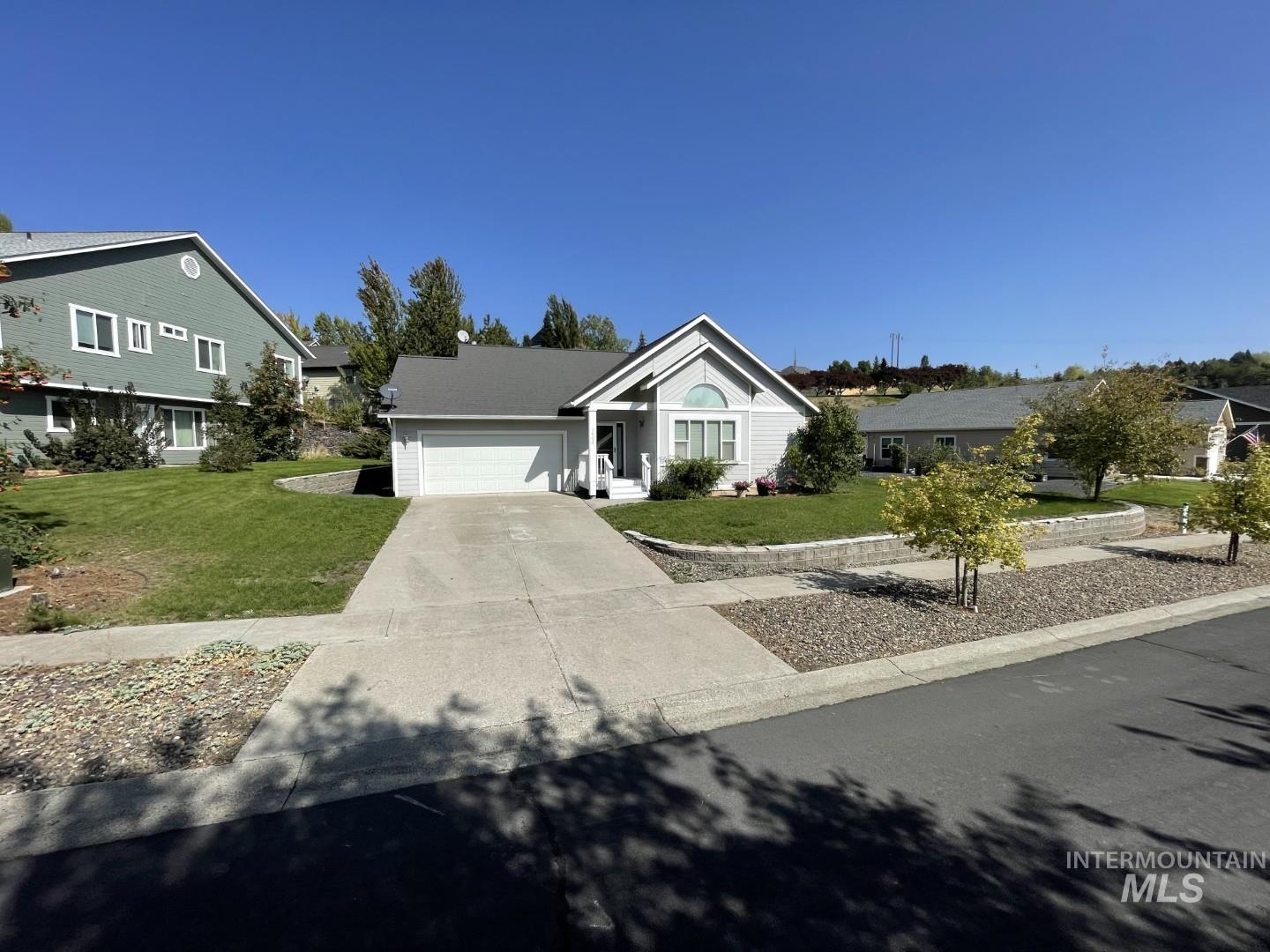 Ranch-style home with a front yard, driveway, and an attached garage