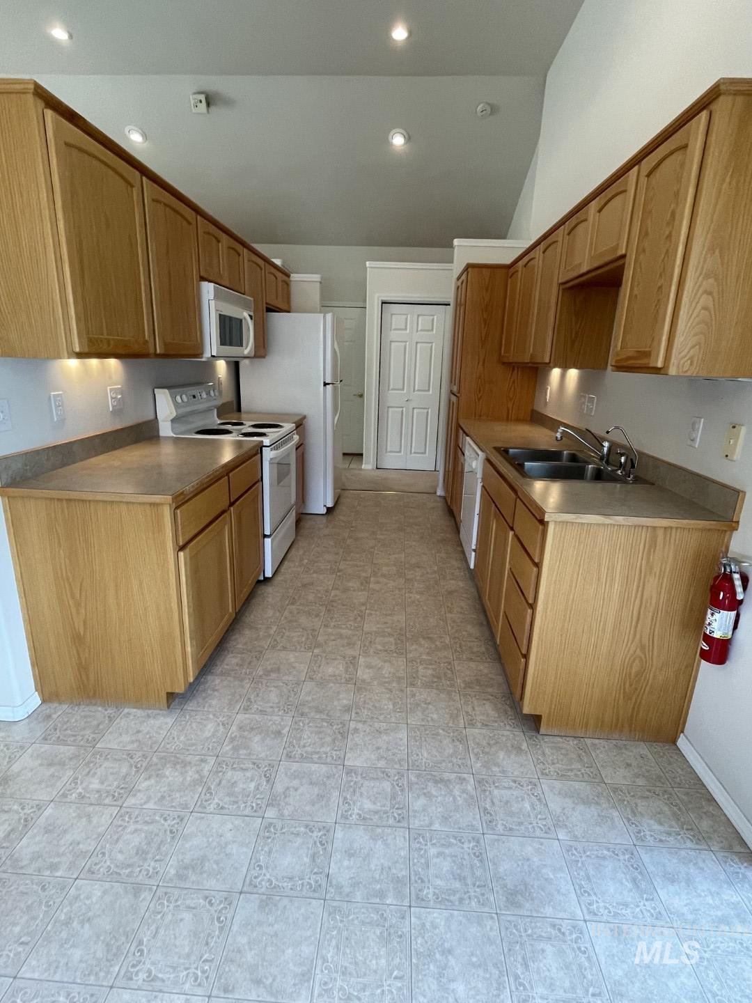 Kitchen with white appliances, vaulted ceiling, and recessed lighting