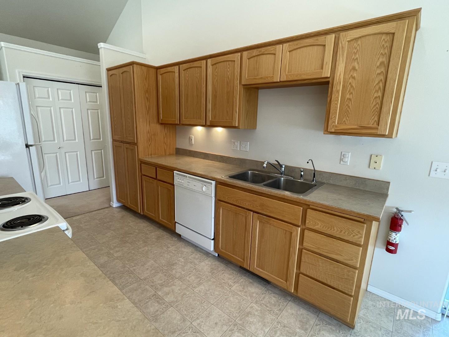 Kitchen featuring white appliances, vaulted ceiling, and light countertops