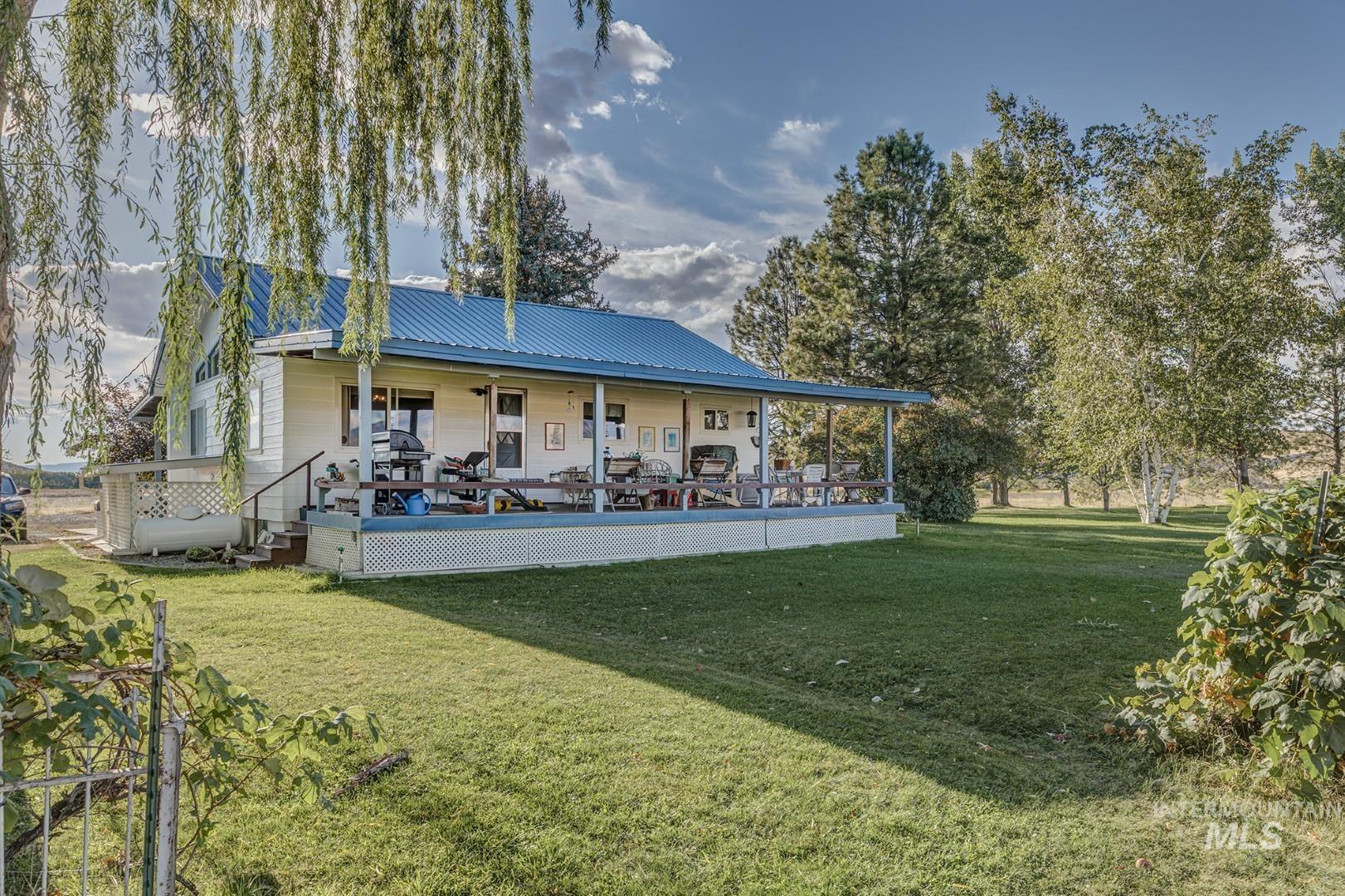 Rear view of house featuring a lawn, a deck, and a metal roof