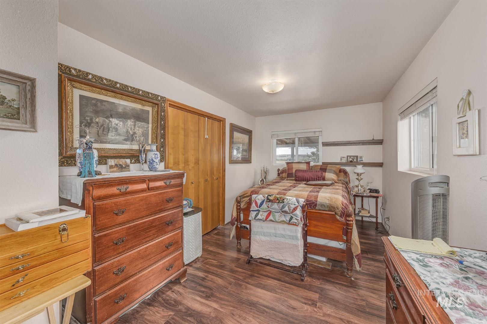 Bedroom with dark wood-style flooring and a closet
