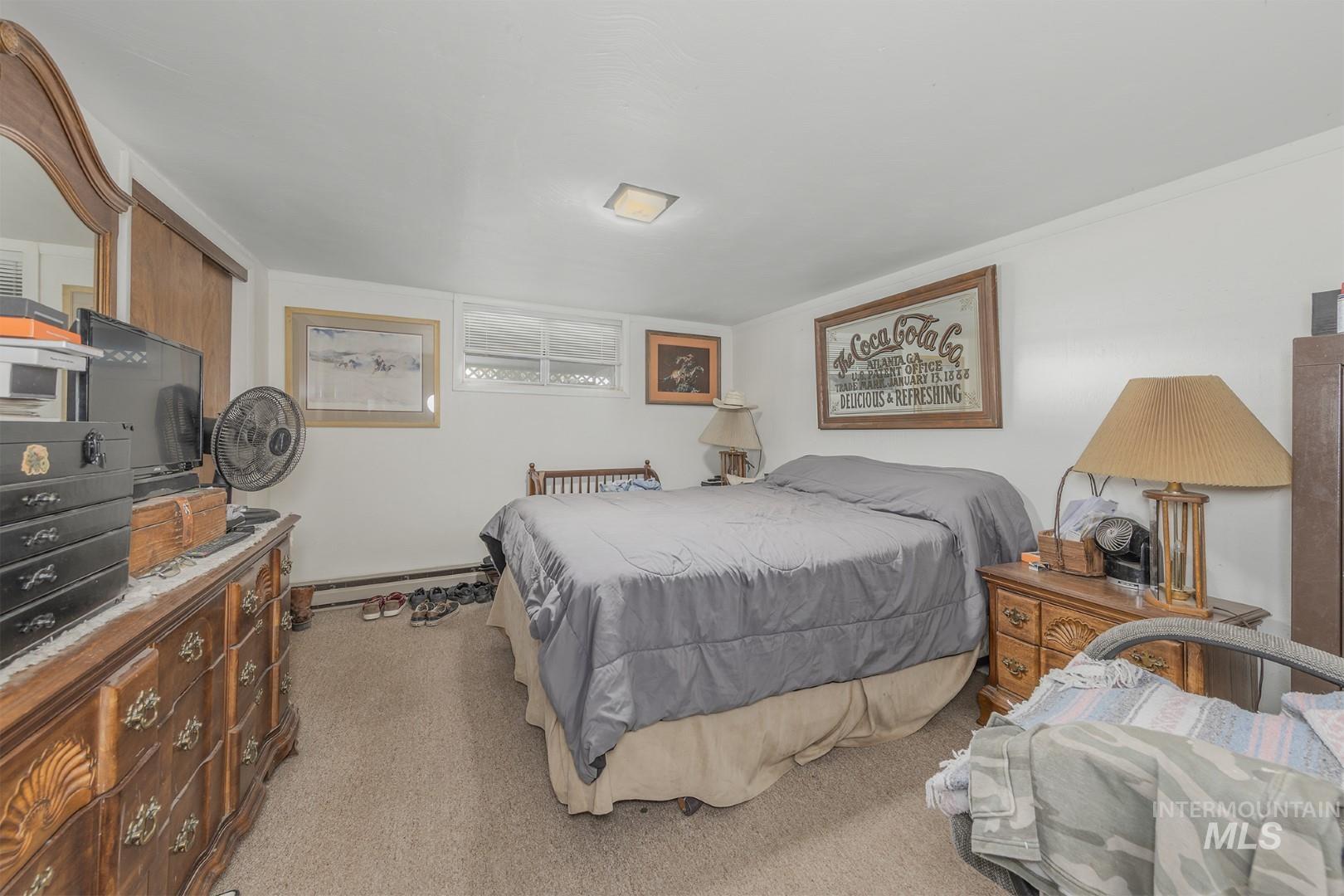 Bedroom featuring light carpet and baseboard heating