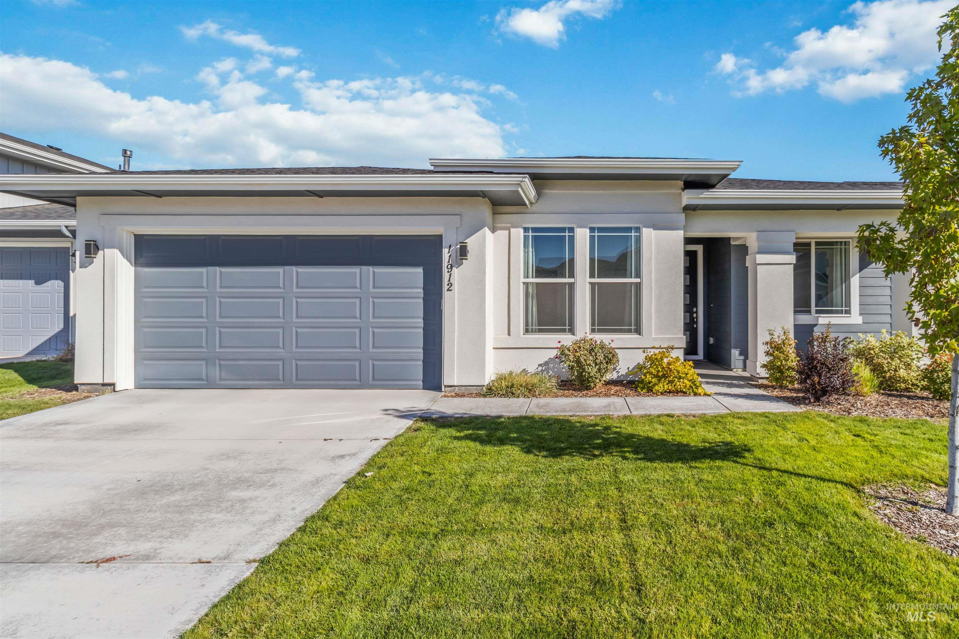 View of front facade with driveway, a front yard, an attached garage, and stucco siding