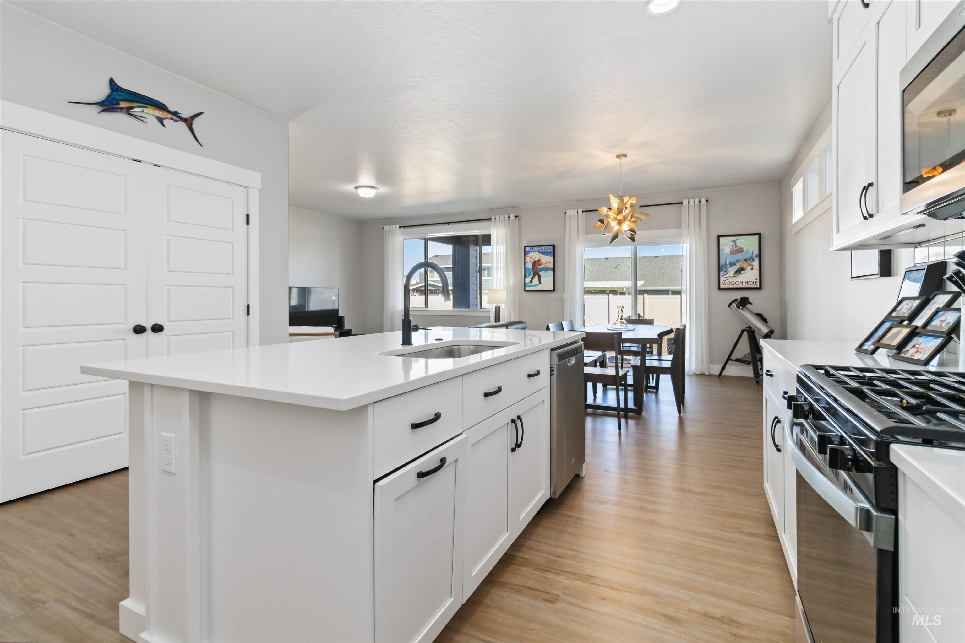 Kitchen with white cabinetry, stainless steel appliances, and light wood-style flooring