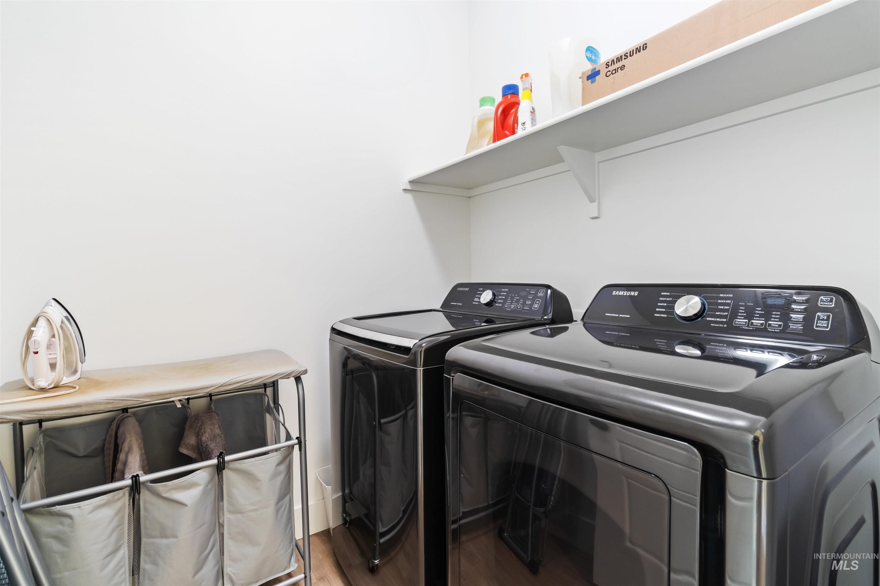 Laundry area with separate washer and dryer and wood finished floors