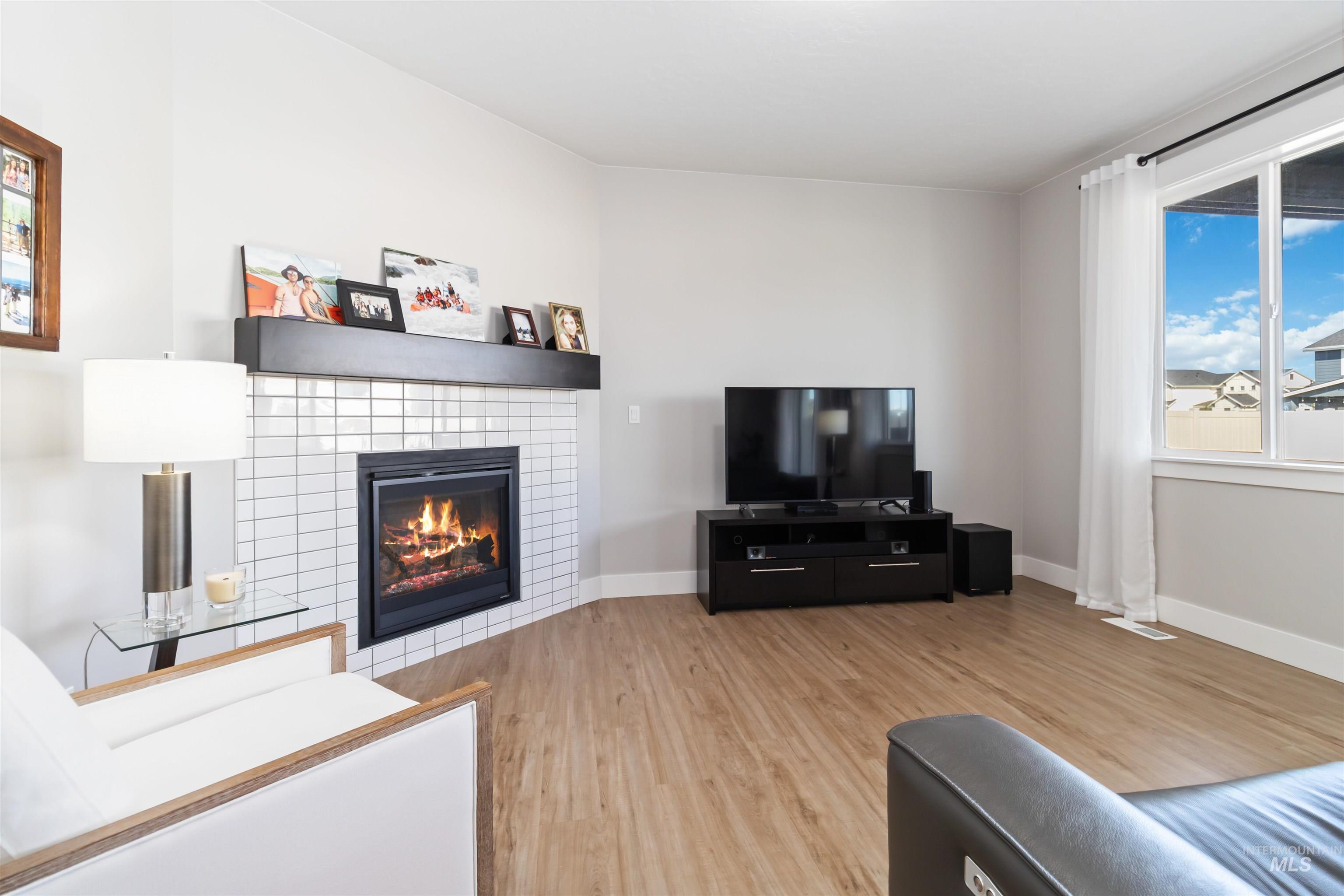 Living room featuring light wood-style floors and a tiled fireplace
