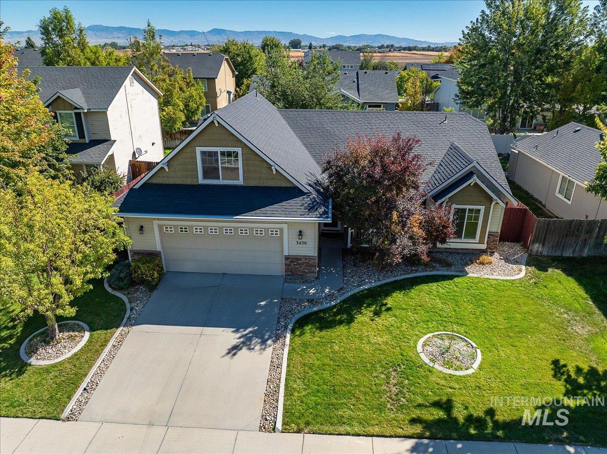 View of front of home featuring concrete driveway, stone siding, a residential view, a garage, and roof with shingles