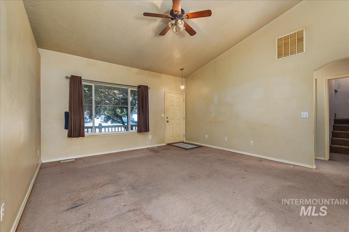 Unfurnished room with carpet floors, a ceiling fan, a textured ceiling, high vaulted ceiling, and stairway