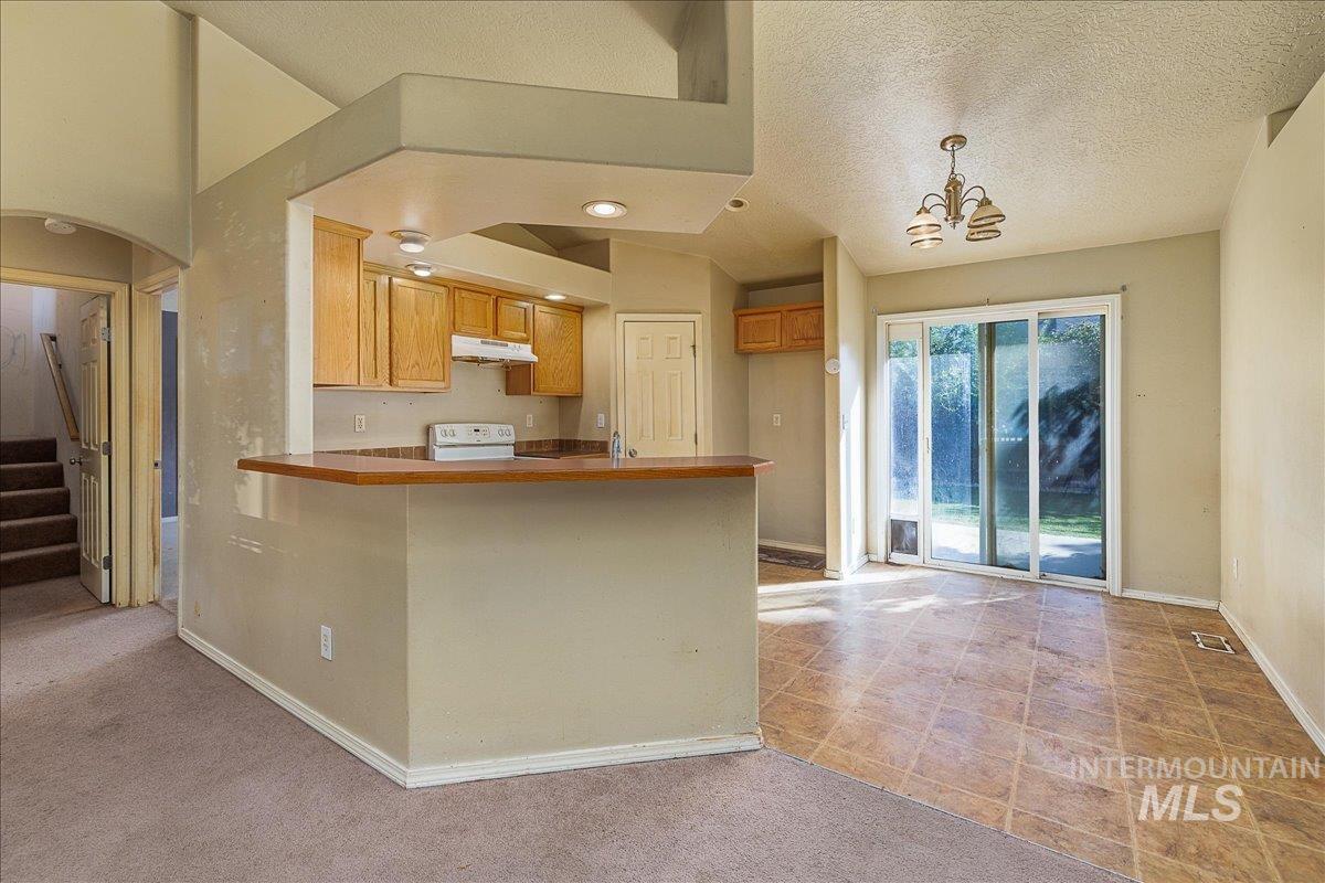 Kitchen featuring a peninsula, decorative light fixtures, arched walkways, a chandelier, and a textured ceiling