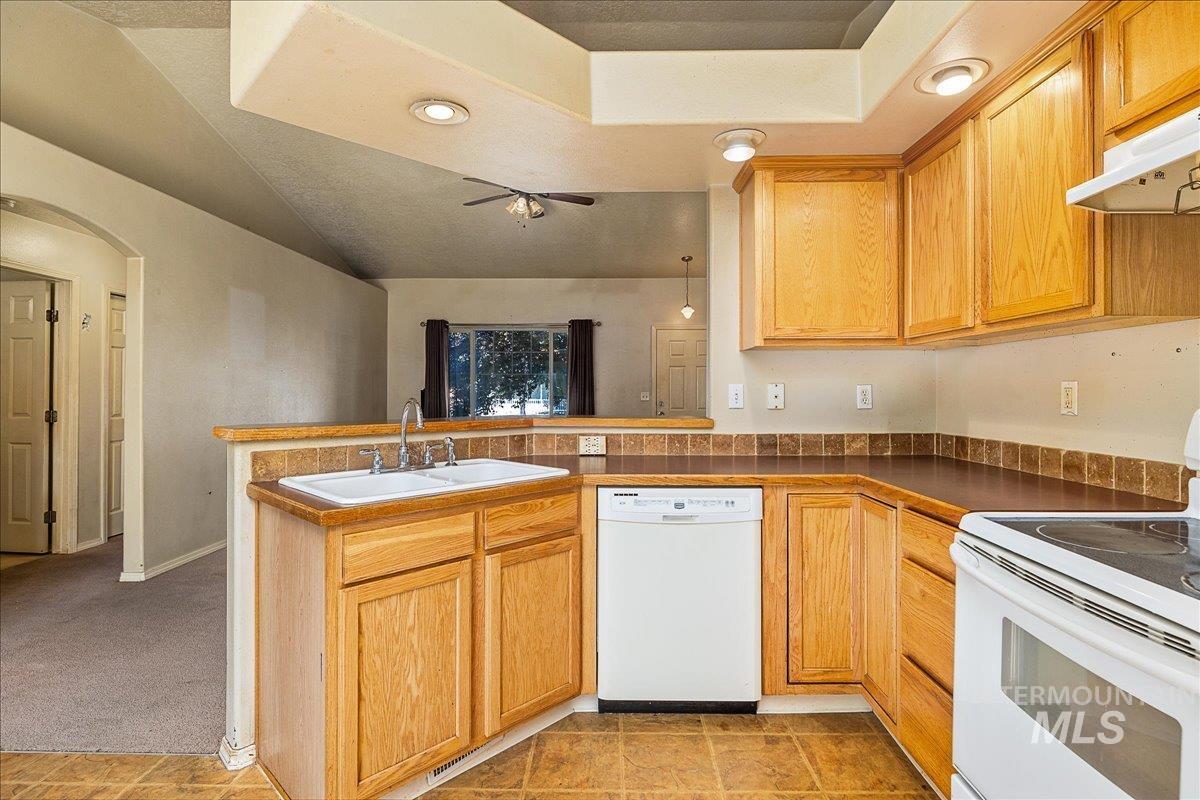 Kitchen with white appliances, a peninsula, under cabinet range hood, ceiling fan, and recessed lighting