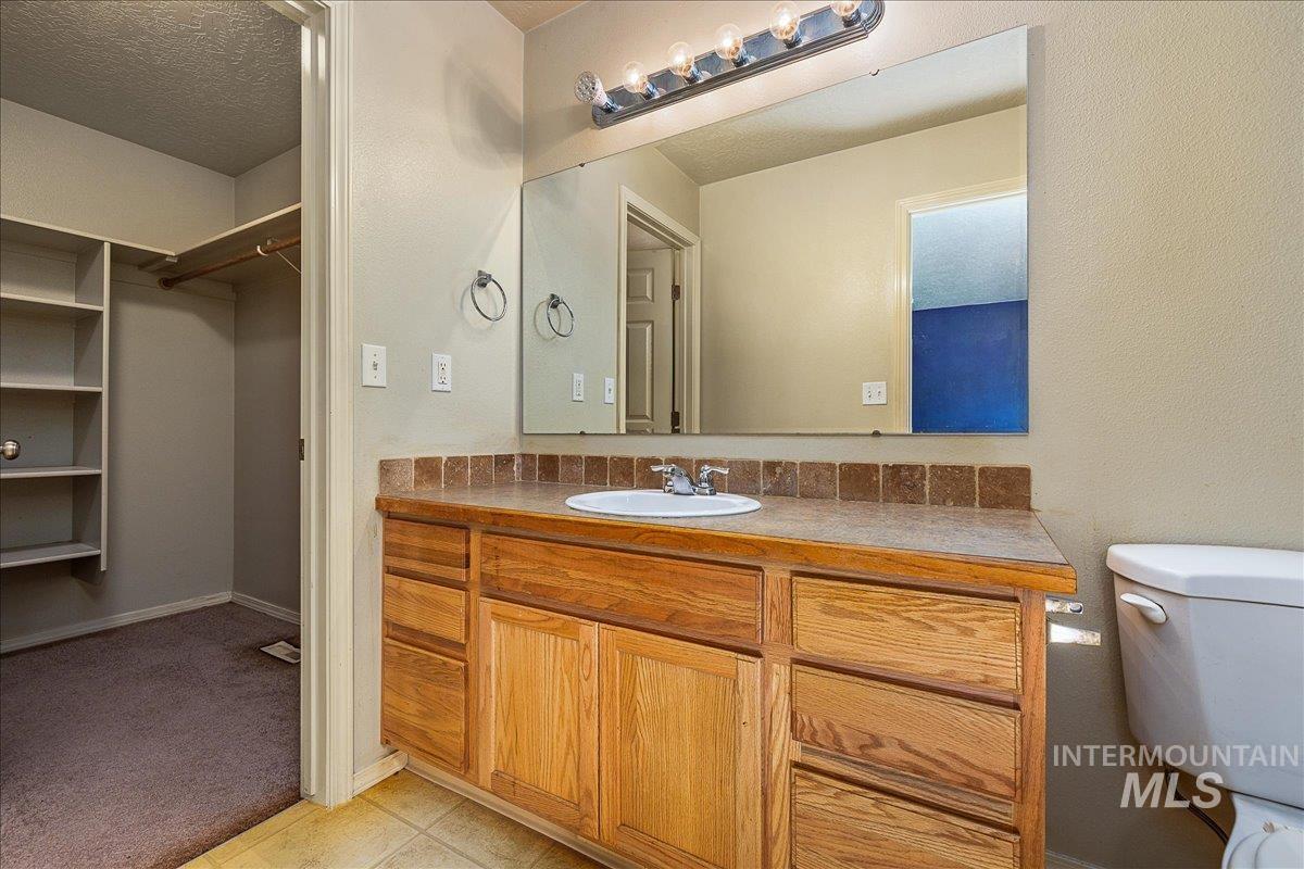 Bathroom with vanity, a textured ceiling, and a spacious closet